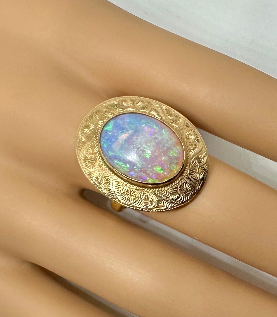 Indulge in a stunning Antique Victorian to Art Deco Six Carat Opal Ring with a gorgeous Opal set in a 10 Karat Gold engraved setting of great beauty.  The spectacular oval opal cabochon gem is 16mm long and has vivid yellow, orange, blue and green