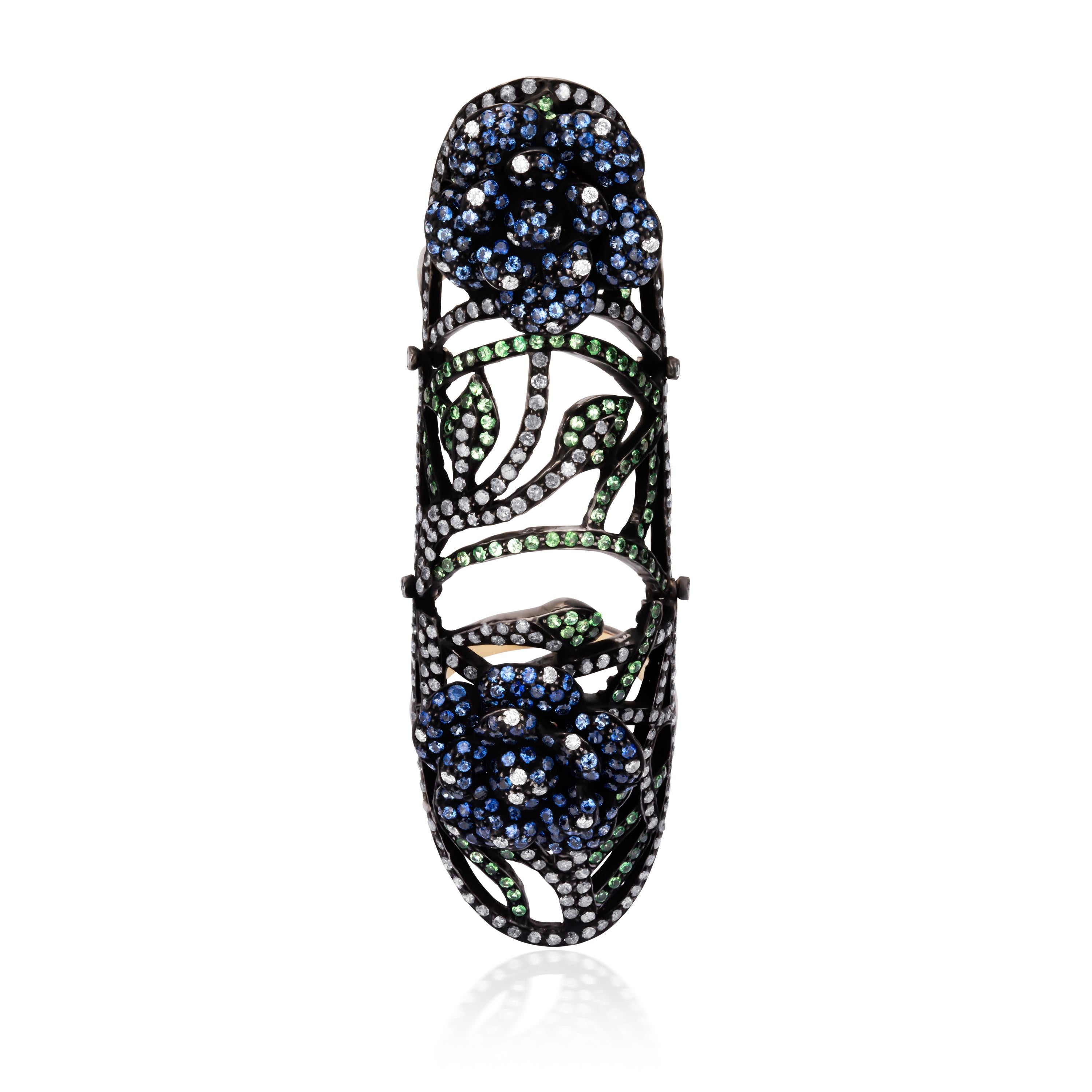 An entrancing design! This classic Victorian cluster ring features sparkling blue sapphires embellished in rose motifs sitting atop a pierced design of tsavorites and diamonds. Handcrafted in 18K gold and 925 sterling silver this ring is accompanied