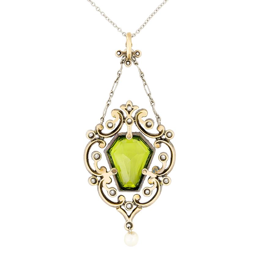 Dating to the Victorian period, this intricately designed necklace centres around a 6.50 carat peridot. An unusual Coffin cut stone, this vivid peridot is completely natural. A total of 1.30 carat in diamonds both surround the peridot and set across