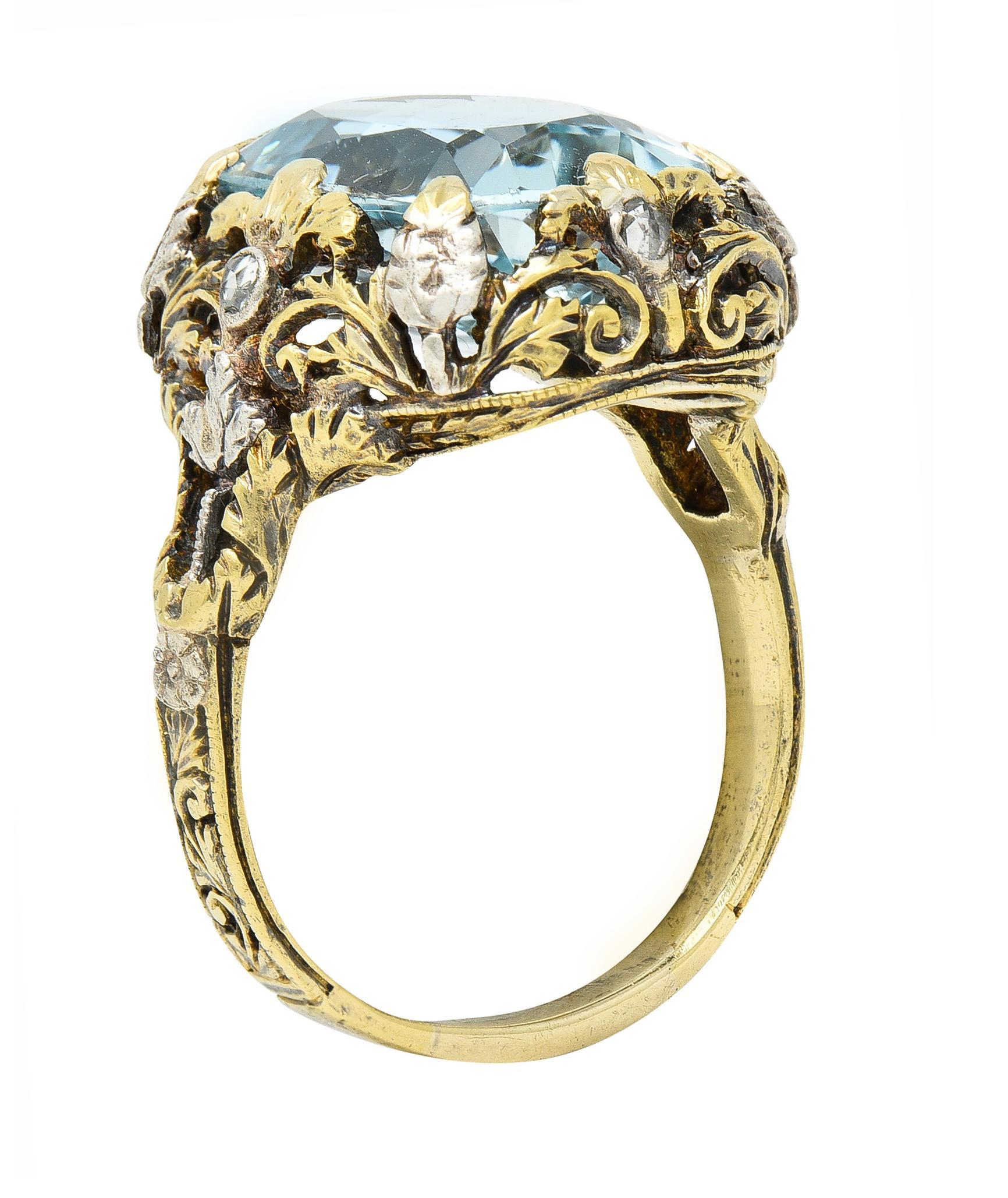 Centering a mixed cushion cut aquamarine weighing approximately 6.40 carats
Transparent light blue in color - prong set in scrolling foliate motif gallery 
Pierced with silver-topped orange blossom flowers at shoulders
With rose cut diamonds bezel