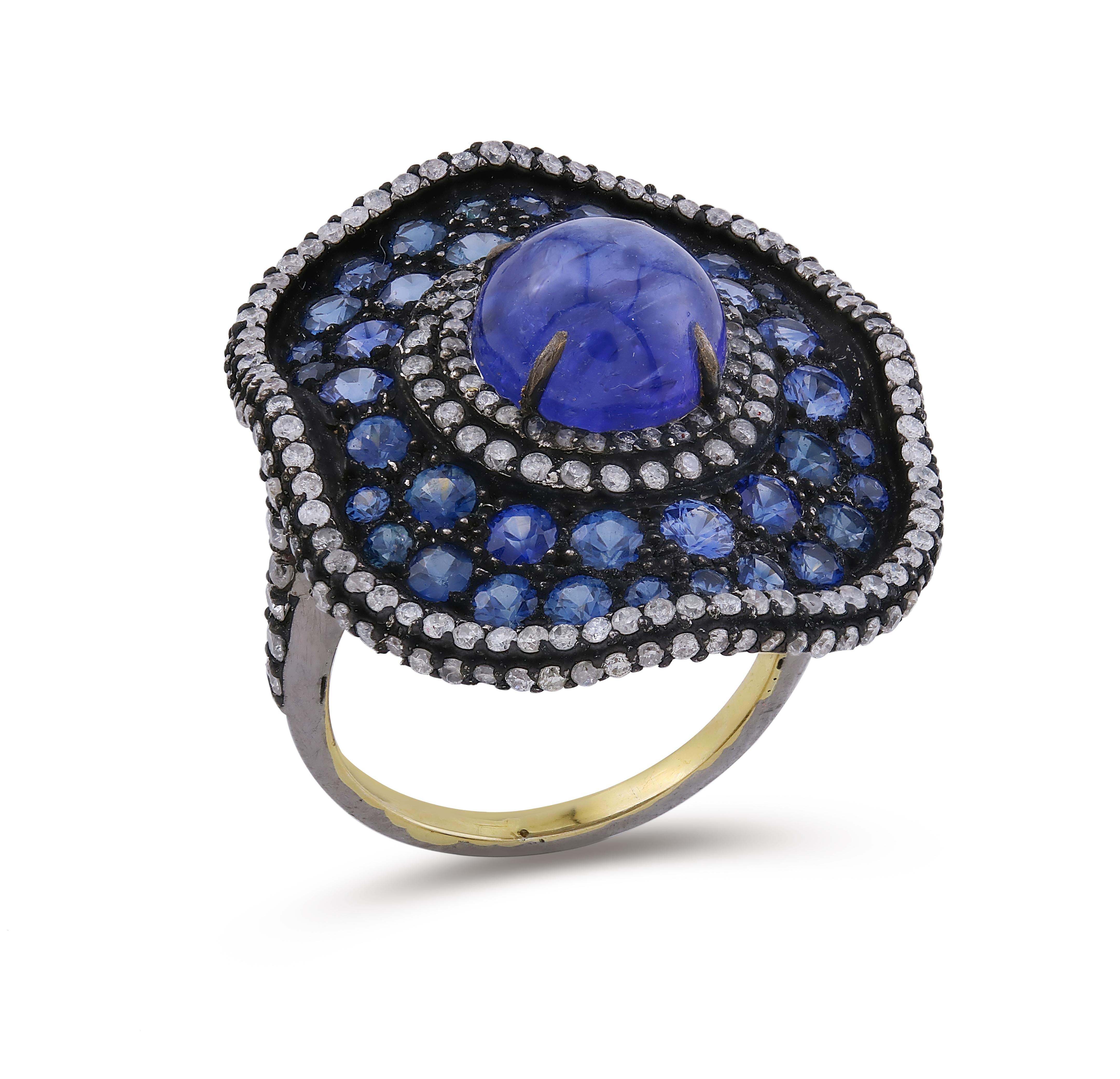 Introducing our exquisite Victorian Floral Cocktail Ring, a mesmerizing work of art that exudes the elegance and opulence of the Victorian era. This magnificent piece features a captivating round cabochon tanzanite, radiant blue sapphires, and