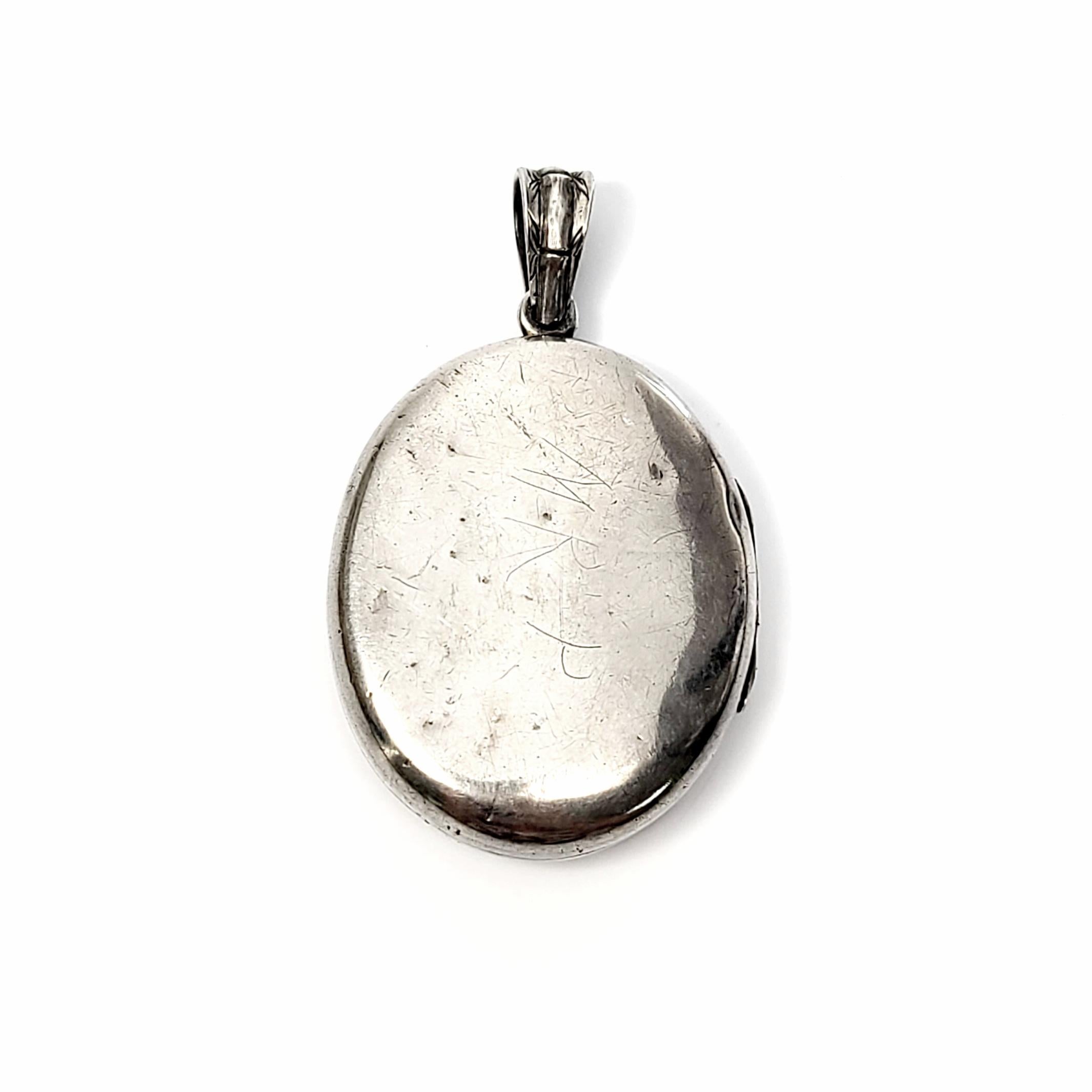 Sterling silver locket of the late 19th century Aesthetic Movement period.

This beautiful antique sterling silver oval locket features an etched design with a gold overlay bird, and a polished smooth back.

Measures approx 2