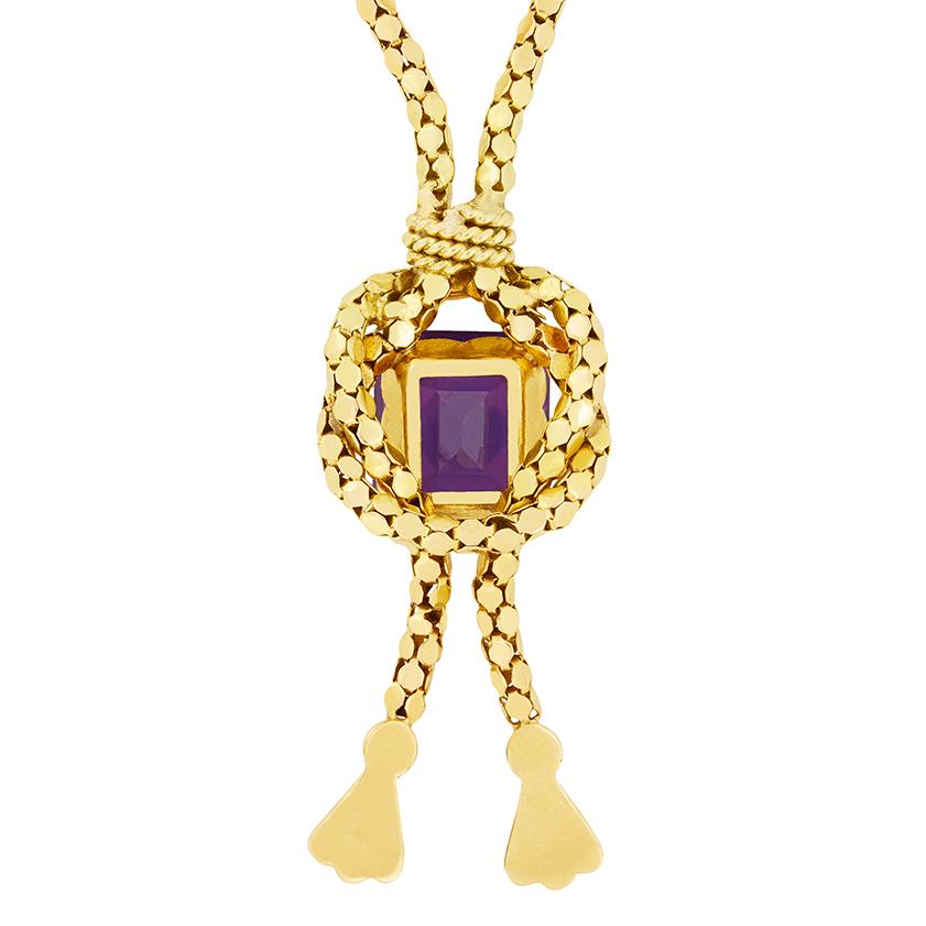 An eye catching 8.20 carat Amethyst sits central to this necklace from the 1880s. The 18 carat yellow gold chain loops around the claw set central gem in a knot like pattern and finishes in two hanging tassels. The chain is 19