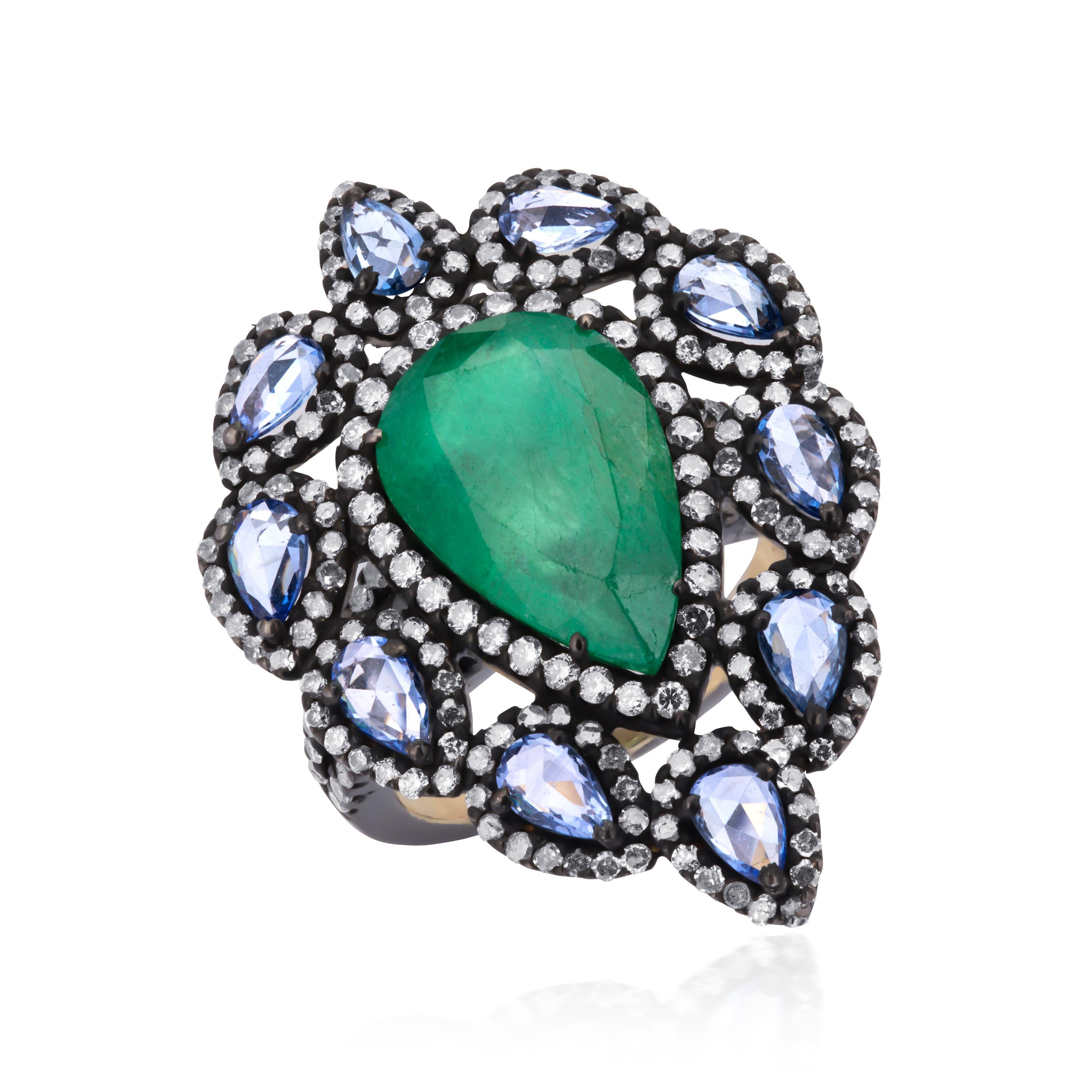 This classic Victorian jewel, hand fabricated in 18K gold and 925 sterling silver, features a vibrant pear cut emerald, weighing 5.44 Cts at the center, surrounded by pear shaped frame of blue sapphires and diamonds. The center design sits