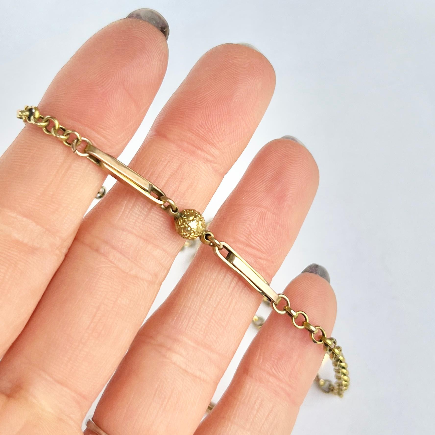 Questa collana in oro giallo 9ct è composta da sottili maglie ovali e da sfere d'oro con dettagli intricati. La catena si chiude con un fermaglio a barile e ha un aspetto delicato ed elegante. 

Lunghezza: 41,5 cm 
Larghezza: 2 mm 
Diametro del