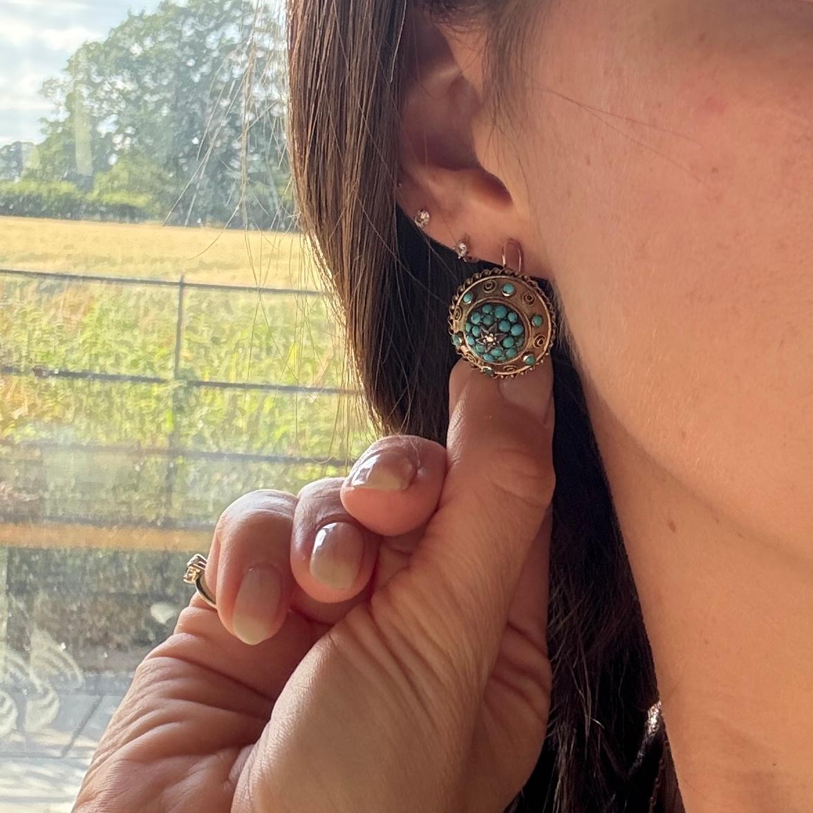 Une magnifique paire de boucles d'oreilles en forme de cible, de style victorien ancien. Chacune est centrée sur un diamant taillé en rose dans une monture en étoile, entouré d'une turquoise naturelle taillée en cabochon. Cette grappe est également