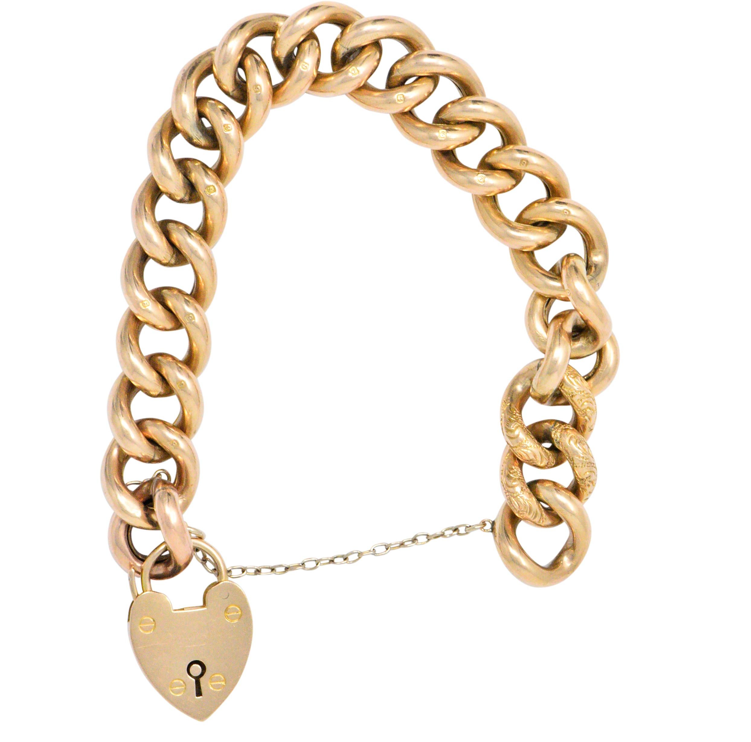 Charm bracelet comprised of puffed curb links

With accent links hand engraved with stylized rose and foliate motif

Featuring a dangling heart shaped padlock with prominent screw head motif and keyhole recess

Padlock acts as clasp complete with