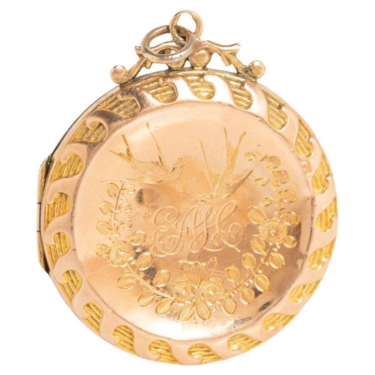 This beautiful and large 9ct gold back & front Victorian Aesthetic round locket was made circa the 1900s. The locket depicts a pair swallows in the flight surrounded by a garland of flowers. It has been engraved with letters on the front and
