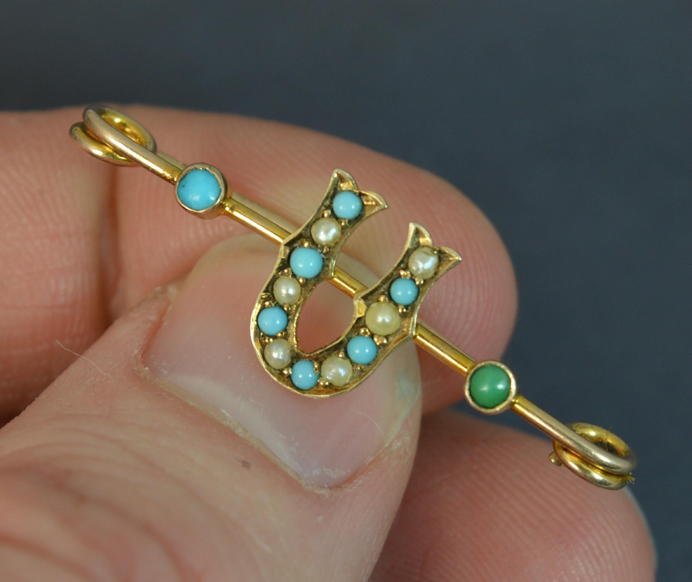 A true antique Murrle Bennett and Co pin. Modelled in solid 9 carat gold. Very finely designed as a U initial set with alternating pearls and turquoise stones and a turquoise to each side. 36mm long. 1.3 grams.
Condition ; Very good. Crisp piece.