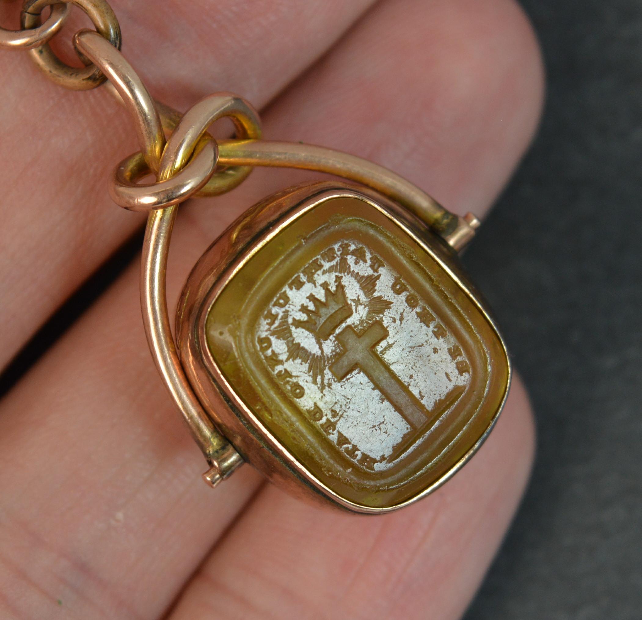 A Victorian period solid 9 carat rose gold tbar, chain and swivel fob.

The swivel is a citrine coloured glass piece with intaglio to each side.

By Honesty engraved above with a person and globe to the centre of him to one side.
Be Thou Faithful