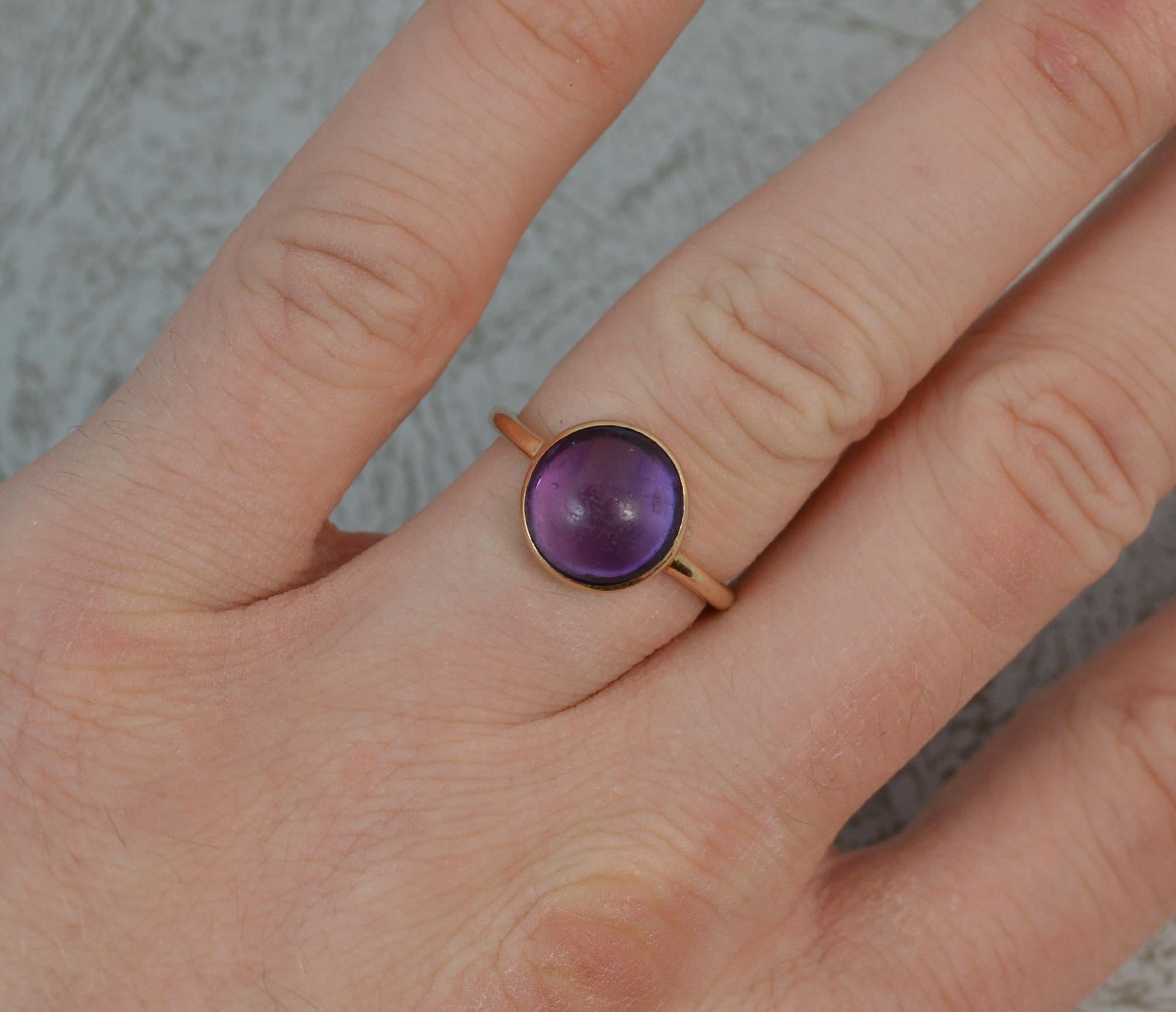 A Victorian solitaire cluster ring in 9 carat gold. Designed with a single round amethyst cabochon stone in bezel setting. Plain gold shank.
10mm diameter stone. 2.9 grams.
Size M 1/2 UK, 6 1/2 US. Tests as 9ct.
Good overall condition for age. Clean
