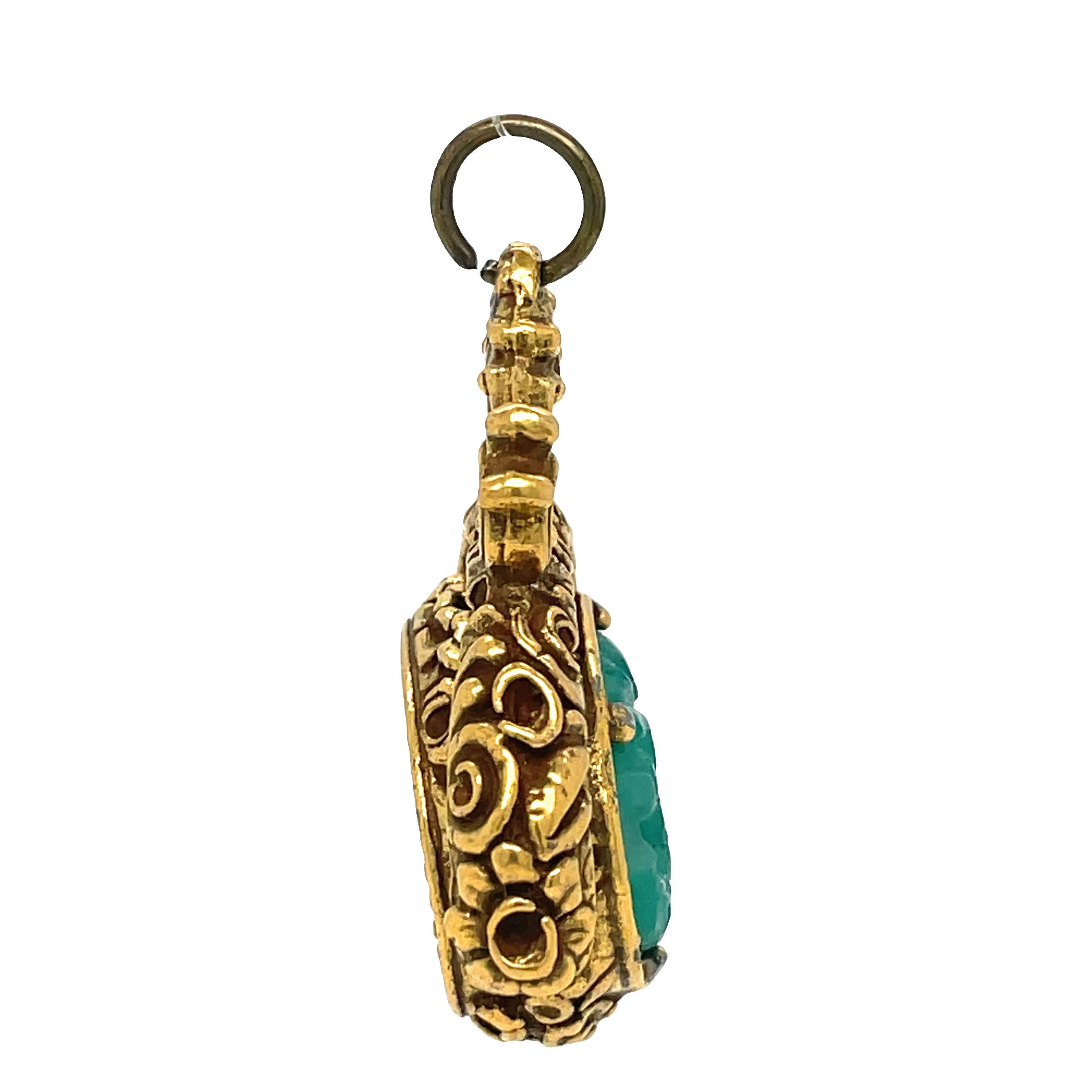 Il s'agit d'un magnifique pendentif de style victorien en or jaune 9 carats. Le pendentif en forme de porte-bonheur est orné de motifs complexes et d'une jade en jadéite sculptée à la main au centre, entourée d'une coquille Saint-Jacques et d'un