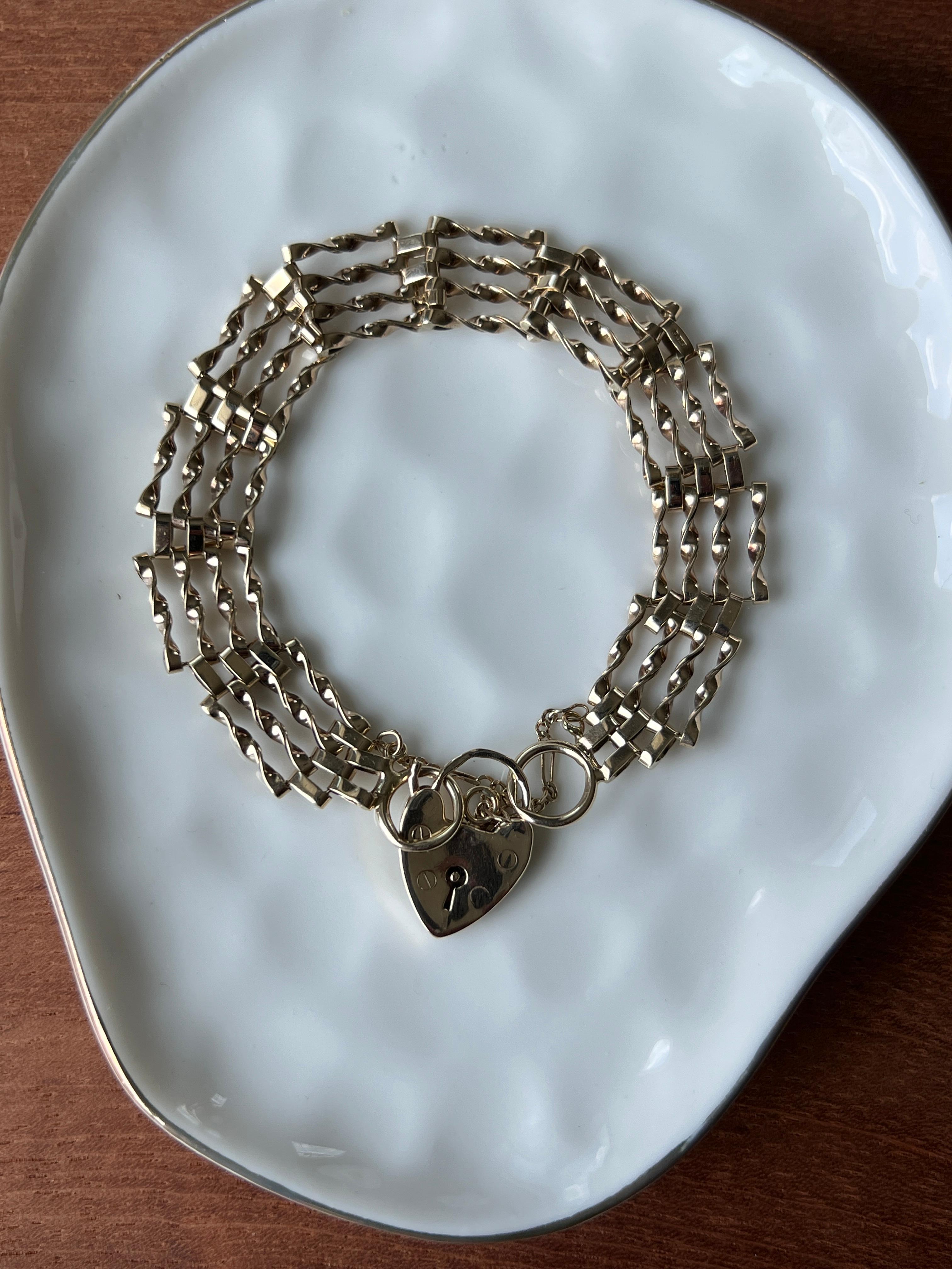 Una pulsera victoriana de eslabones de oro amarillo de 9 quilates, con su cierre original de candado en forma de corazón. Este diseño clásico, de finales del siglo XIX, presenta cuatro filas de eslabones articulados que caen con elegancia sobre la