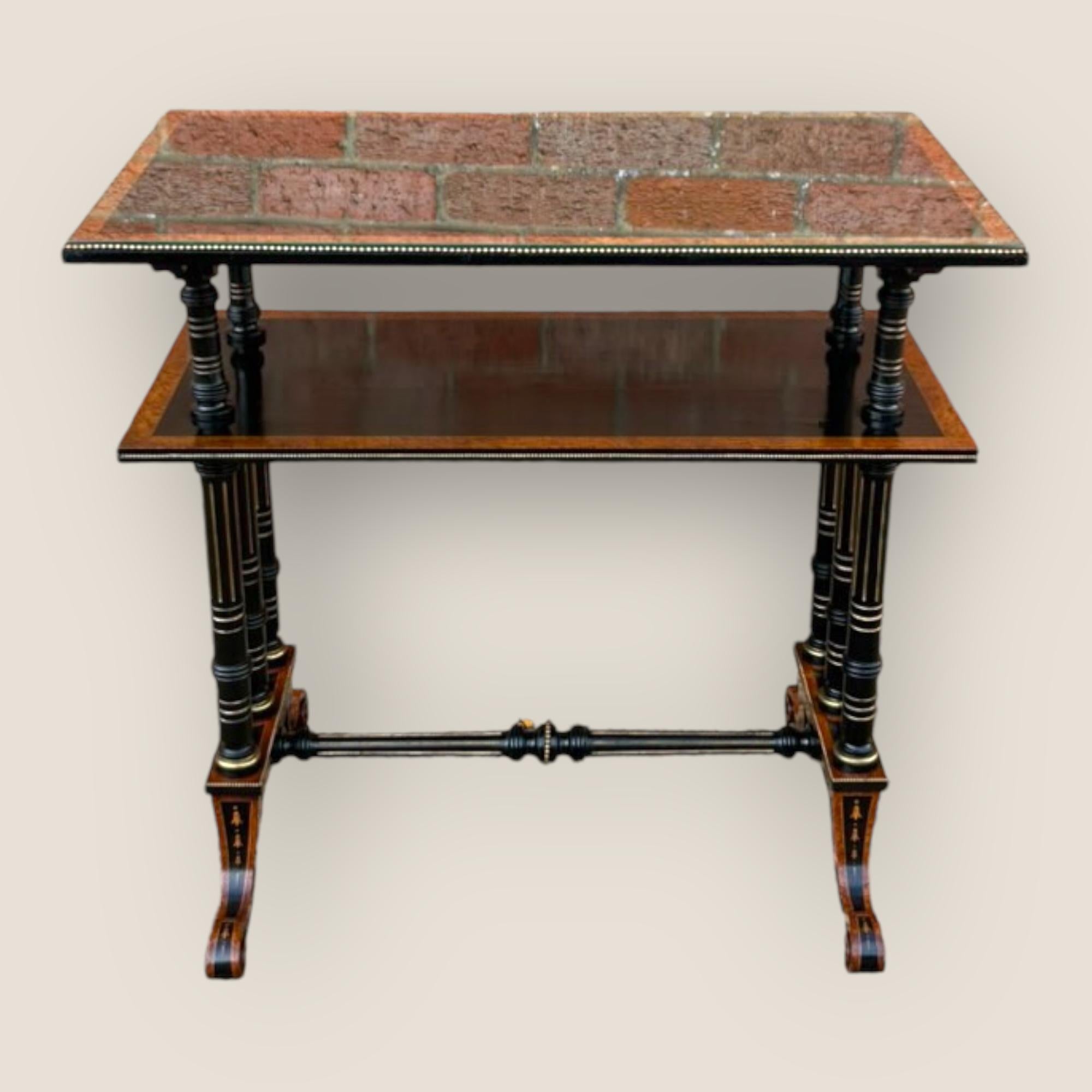 A Victorian Aesthetic Movement Burr Walnut & Ebony Dumbwaiter. Two tiers, inlaid, gilt detailed legs and brass edged top to bottom. Finished off with a glass top. With porcelain casters on the bottom of each foot and carved ebony and gilt support