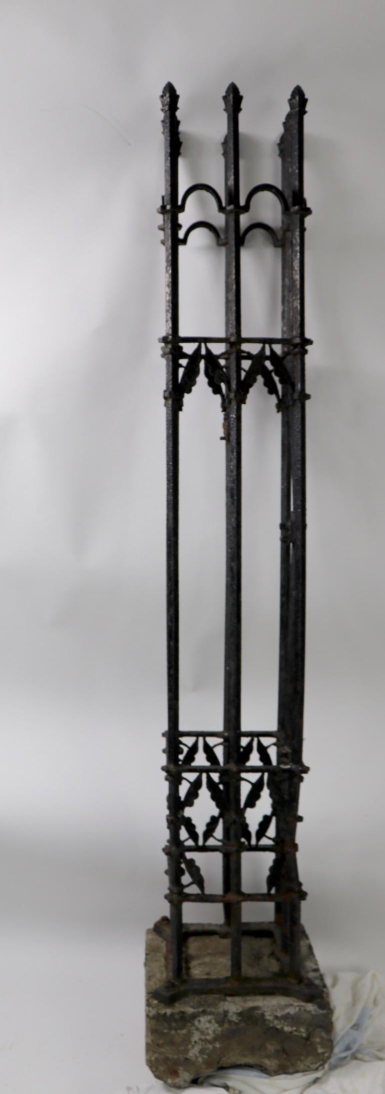 Victorian Aesthetic Movement cast iron fence post having four vertical elements jointed by square iron structural elements. The cast iron post is attached to original cast stone base, which can be set in the ground to display decorative iron post.