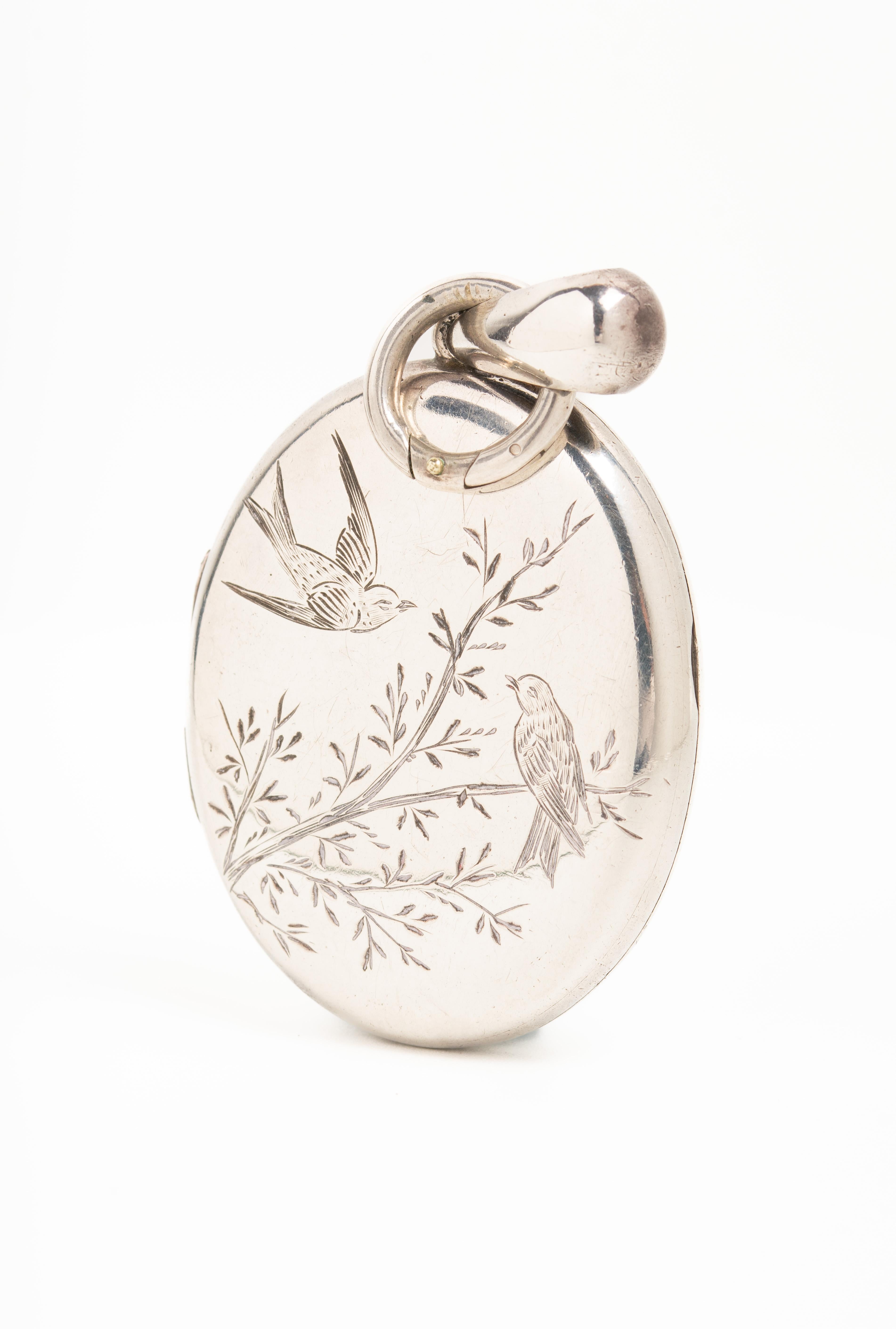 Antique Victorian silver photo locket with a typical for Aesthetic movement design. The front of this beautiful piece depicts a pair of swallow birds, one in a flight and another one sitting on the branch. The swallow was very popular in the