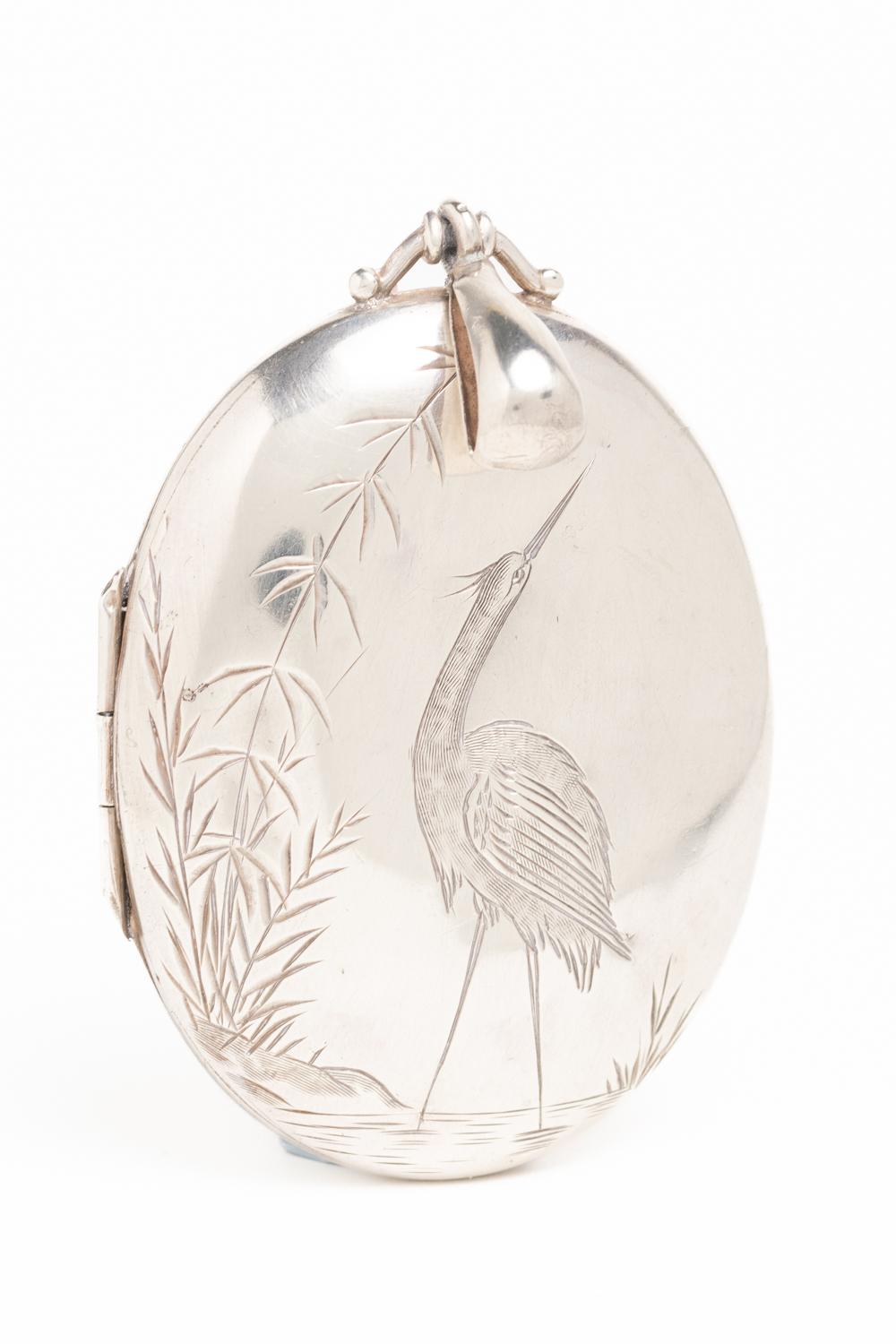 Antique Victorian sterling silver locket dated 1876. This extraordinary silver locket is hallmarked for Birmingham and made by Horace Woodward & Co. The front depicts a Japonesque-style scene, a heron in the centre of the piece standing among
