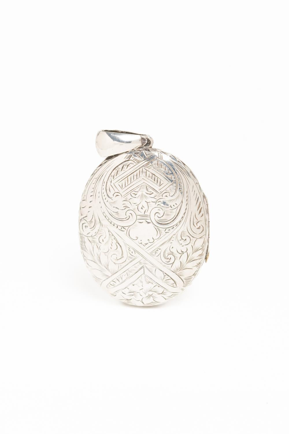 This gorgeous antique sterling silver large oval locket dated 1879. Beautifully engraved with a floral motif in the from of the locket and a geometric, scrolled motif on the reverse. Distinctively different designs on the from and back make this