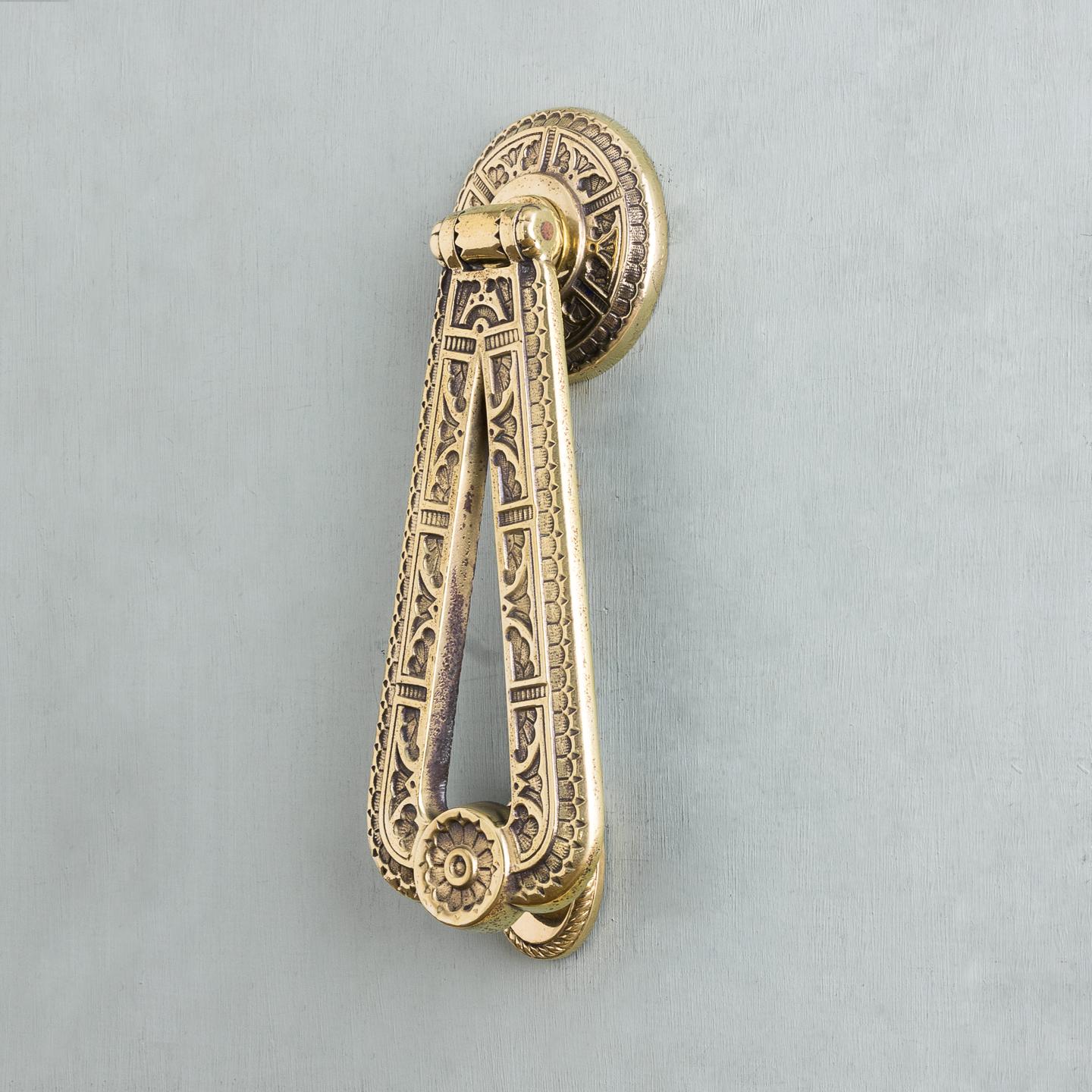 A Victorian Aesthetic period brass door knocker with associated striking plate, circa 1870-1880.