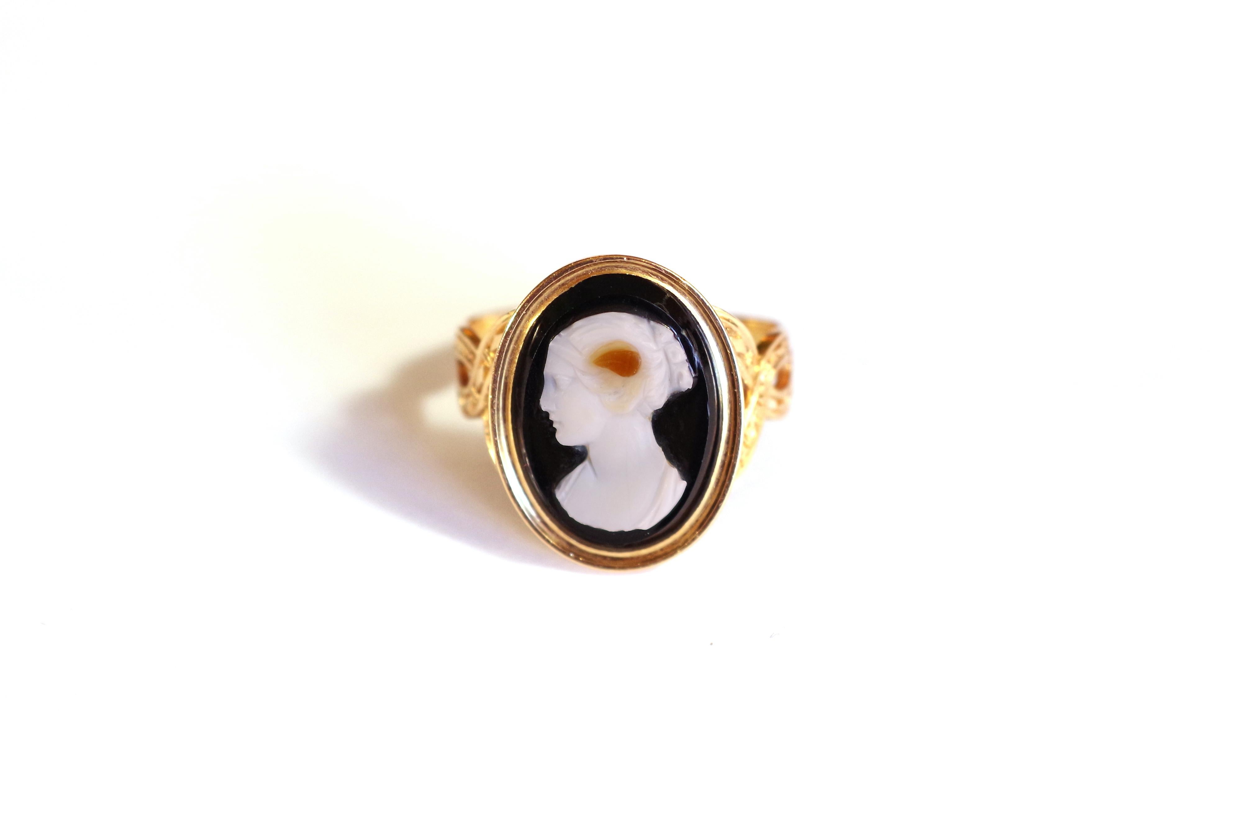 Victorian agate cameo ring in 18 karat pink gold. In the center, a black and white multilayer agate carved in relief depicting Flora goddess in profile. The central stone in bezel setting. Two intertwined strands form the ring, one decorated with