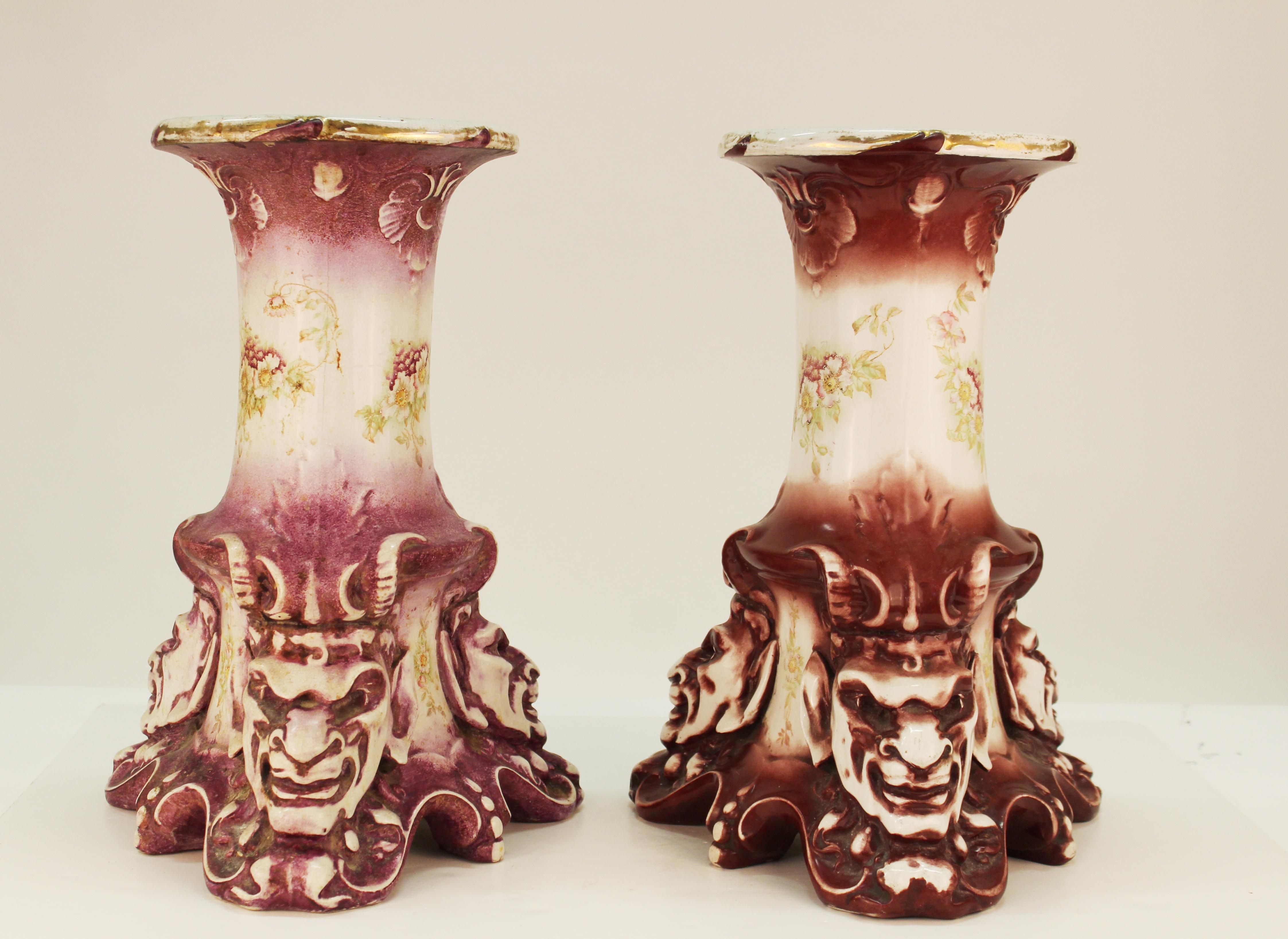 Pair of Victorian period hand-painted ceramic pedestals in grotesque style with horned satyr heads at the base, made by Alba China. The pair is stamped at the bottom with a mark reading 'Bona Fama est mellor zona aurea' ('A good reputation is better