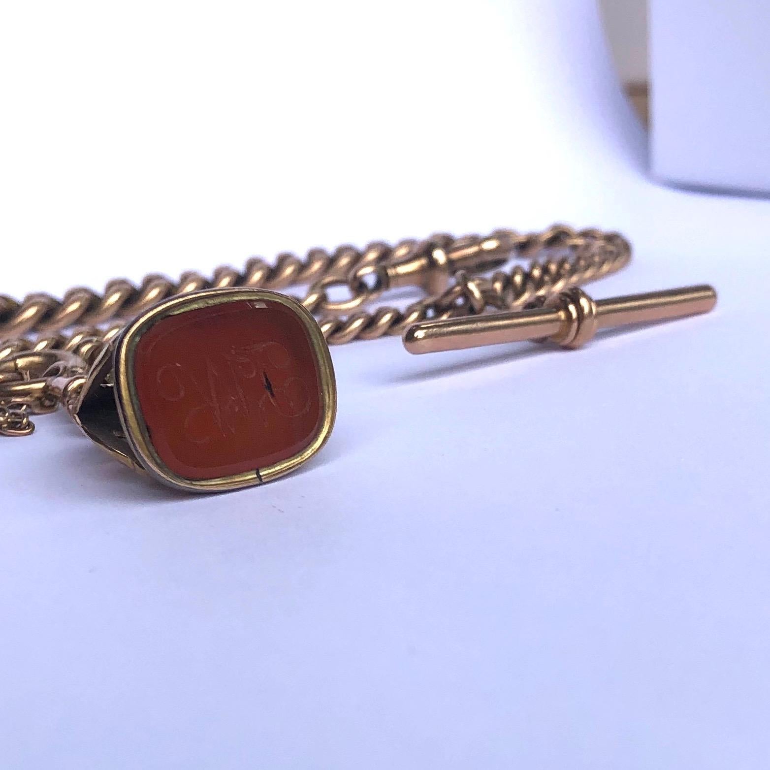 This curb chain is hallmarked on each link and slightly graduates in size starting with the larger links at the centre and smaller on the outside. At one end of the chain is a dog clip and the other has a fob with a carnelian stone engraved with the