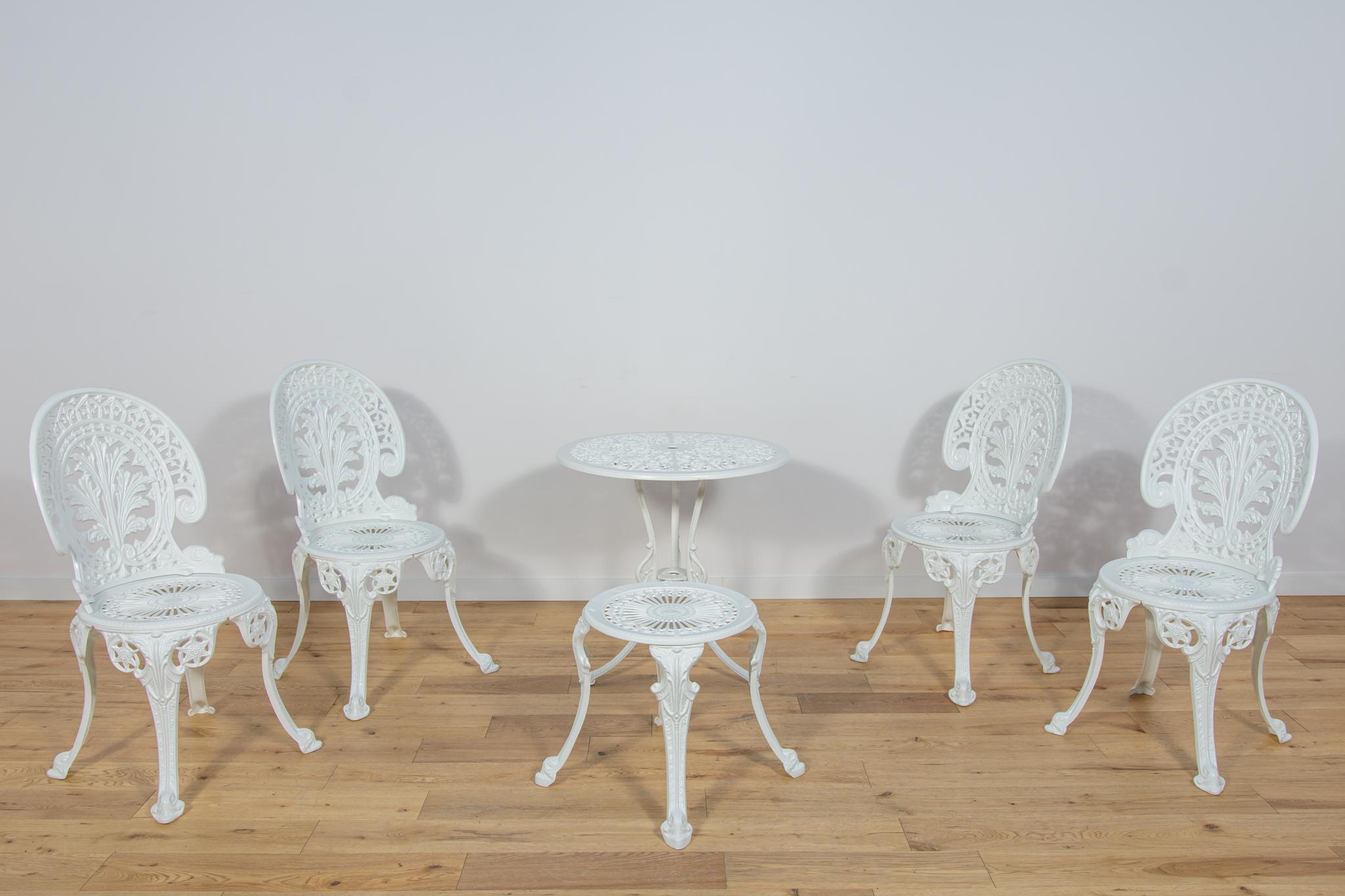 The table and four and stool garden chairs in the Victorian style with floral ornamentation, made in the 1950s in Great Britain. The set after a comprehensive renovation of aluminum elements. Cast aluminum has been refurbished, chemically cleaned of