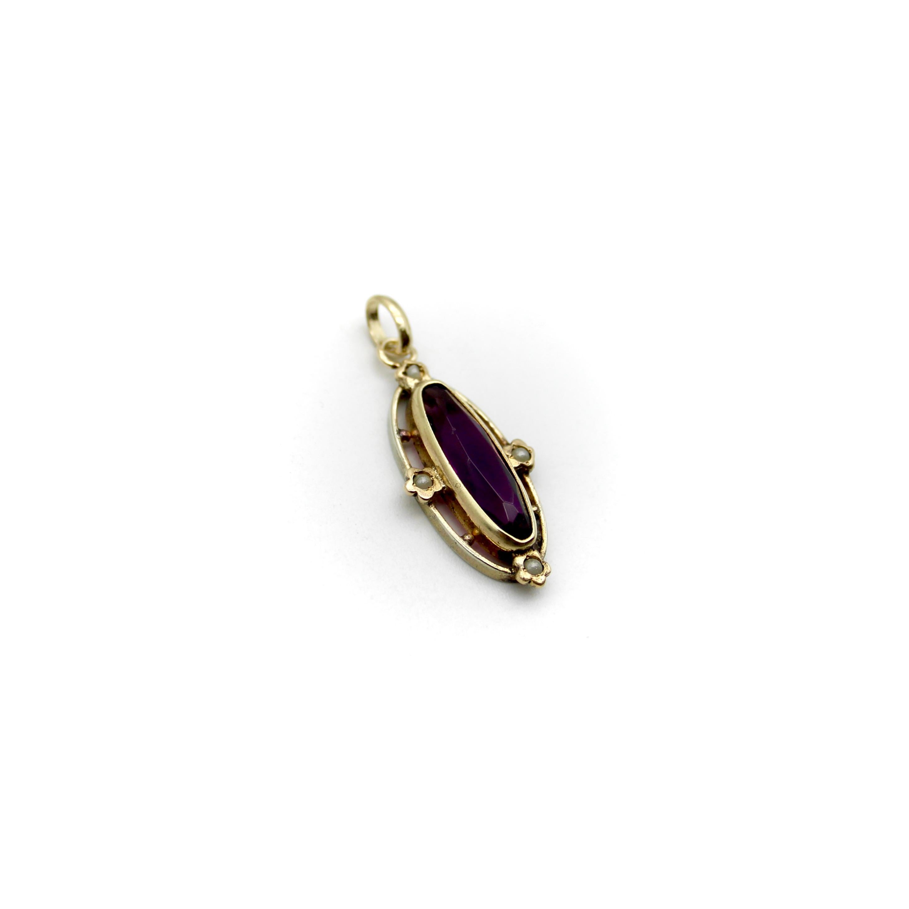 Circa the Victorian era, this elongated oval amethyst makes for a graceful charm or pendant. Seed pearls set into flowers bisect the center gemstone, adding to the femininity of the piece. The flowers and the bezel setting of the amethyst are 14k