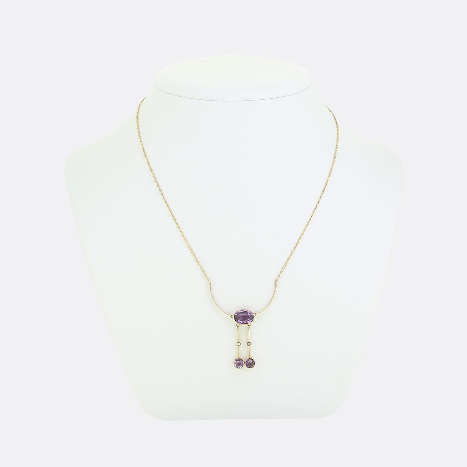 Here we have a charming negligee necklace taken from the Victorian period. A warm 9ct yellow gold belcher chain suspends a duo matching curved bars which themselves play host to an oval faceted rich purple amethyst. A pair of pearl set knife edge
