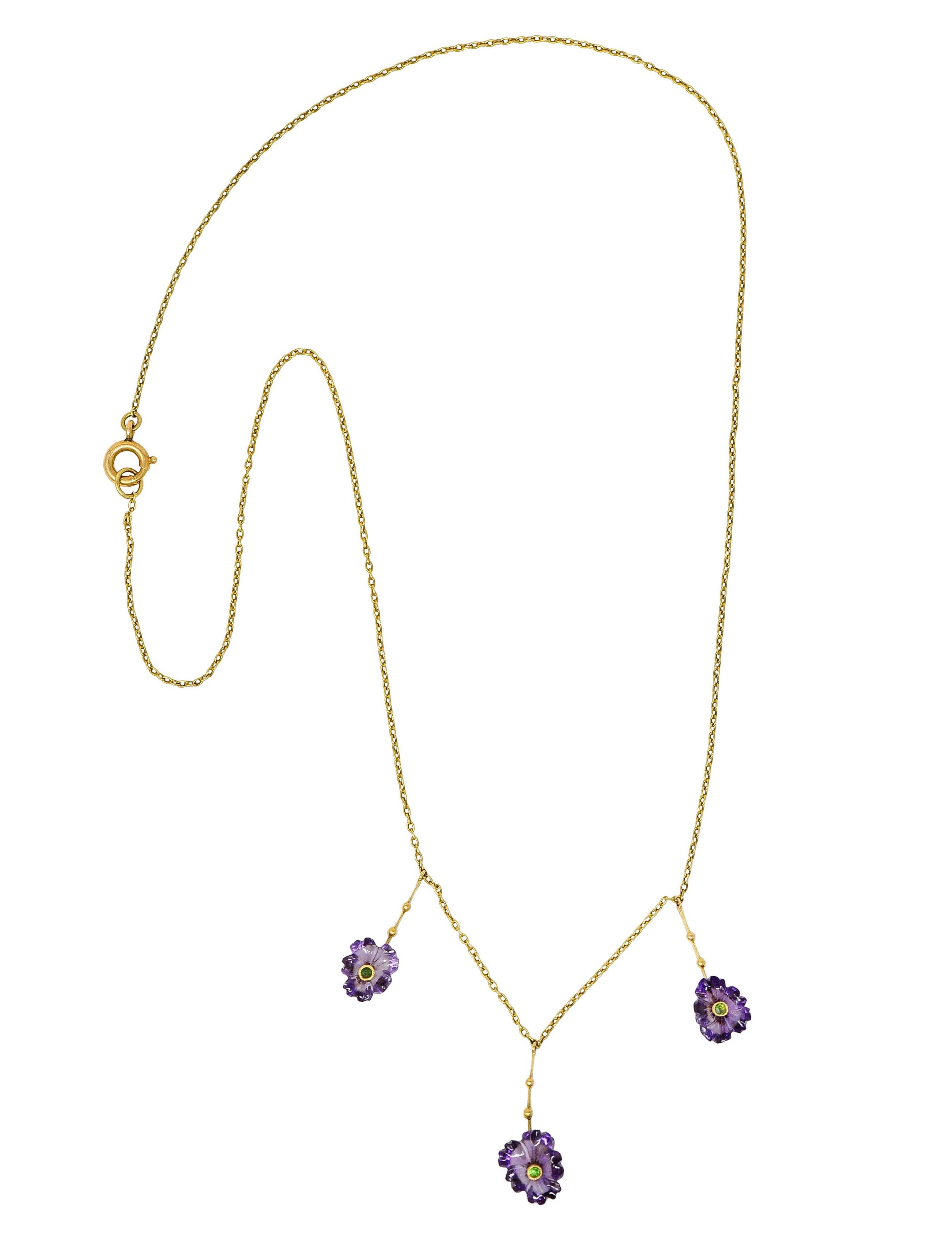 Classic cable chain necklace suspends three drops

With a bar surmounts accented by gold beading

Terminating as carved amethyst flowers - medium to medium light purple in color

Each centering a bezel set round cut demantoid garnet - bright