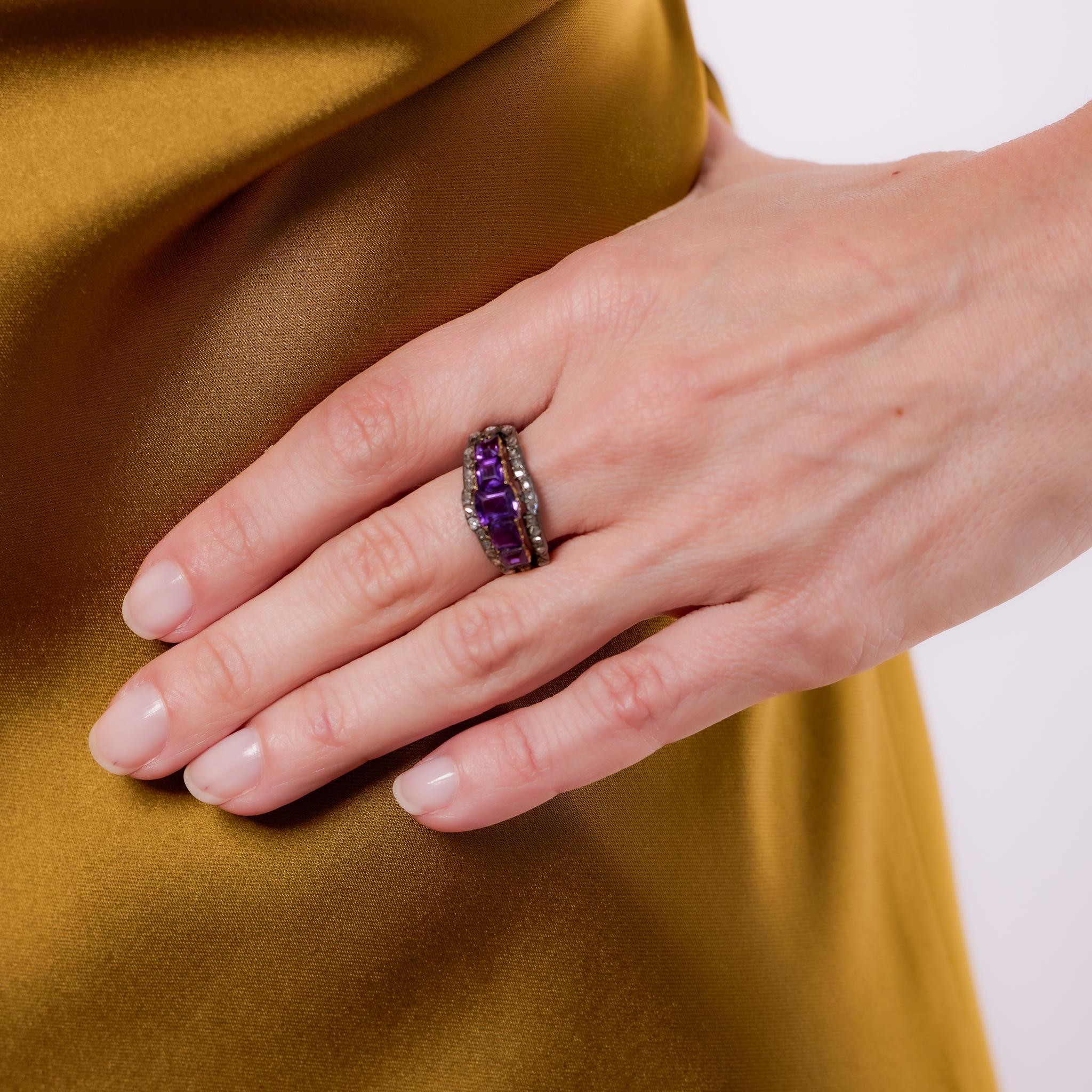Crafted in the 1890s, this Victorian ring is set in 18k yellow gold with a silver top and showcases five emerald cut amethysts totaling approximately 1.60 carats. The vibrant purple stones are beautifully framed by 28 rose cut diamonds totaling