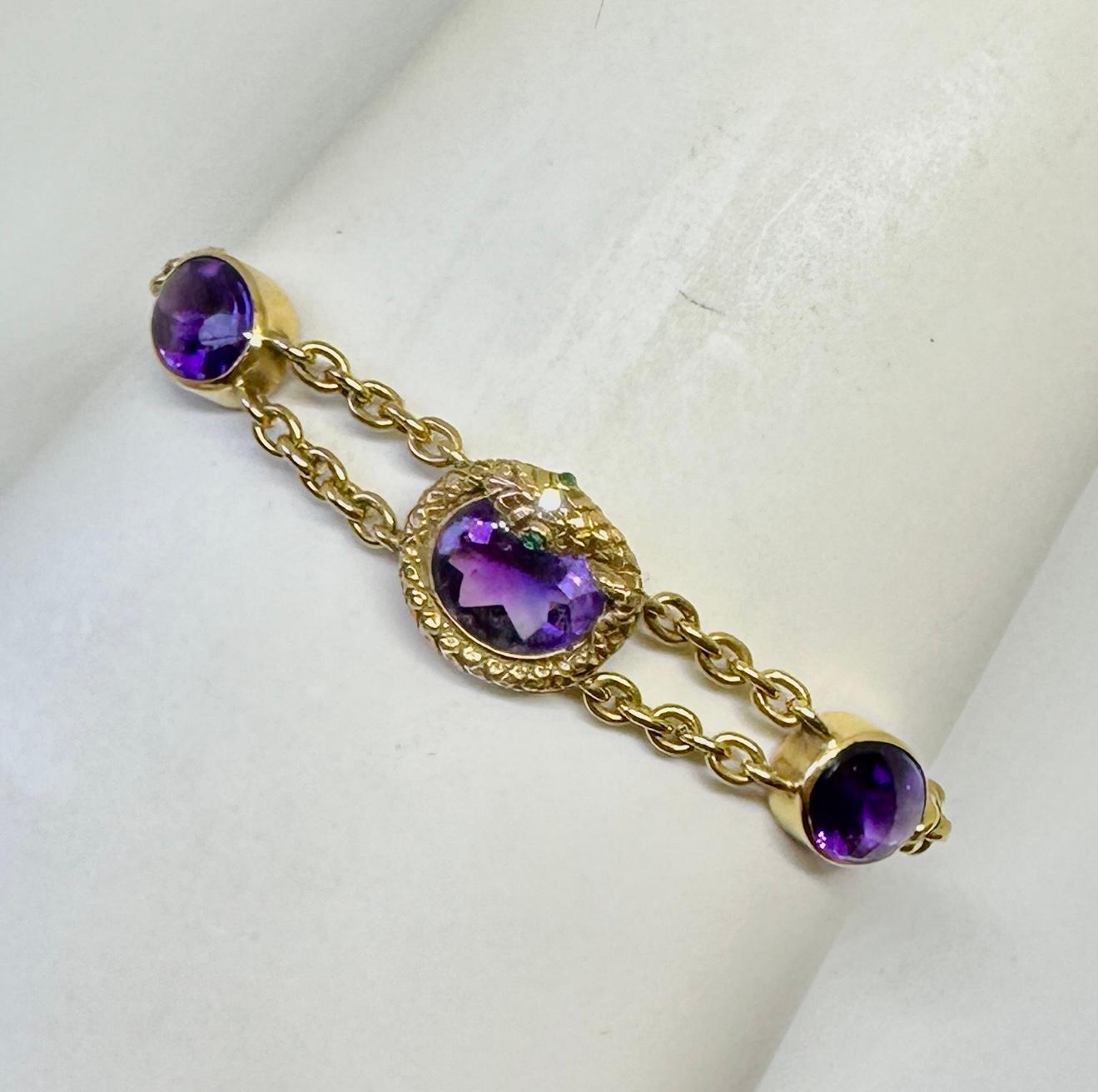 Ésta es una rara y maravillosa pulsera serpiente victoriana antigua con gemas de amatista púrpura real, ojos de esmeralda y un diamante de talla europea y en oro de 14 quilates.  La impresionante joya está centrada con una serpiente enroscada