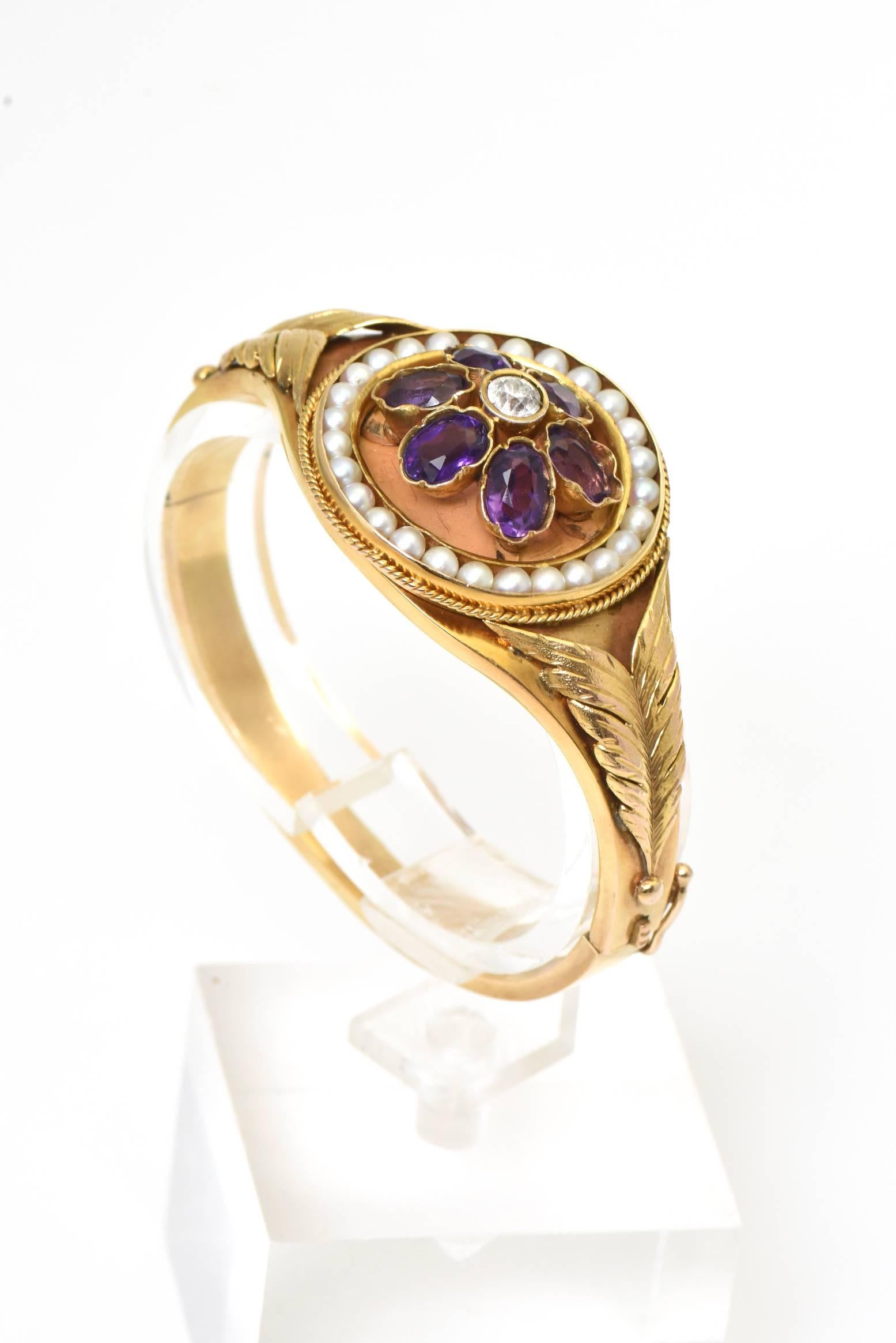 Gorgeous Victorian 14k yellow gold bangle bracelet is beautiful condition.  This bracelet features to highly stylized leaves (or feathers) leading up to a centrally set circle that has a amethyst flower with a diamond center within a channel set in