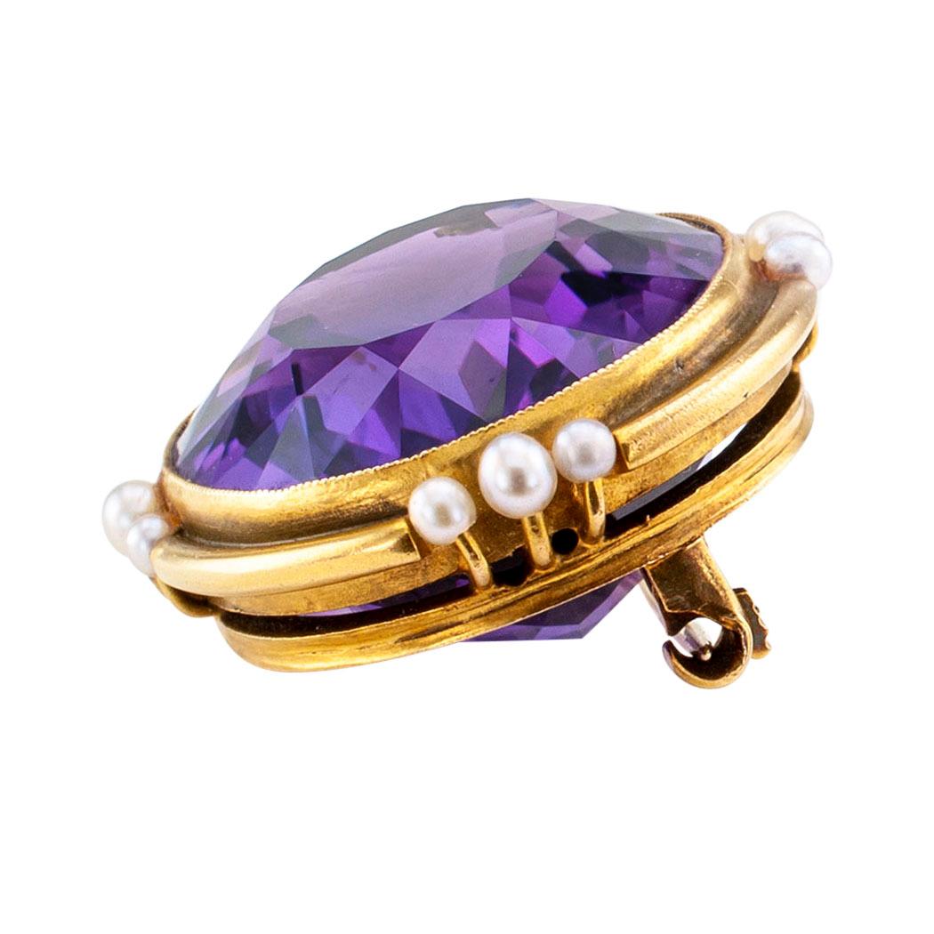 Antique amethyst seed pearl and gold brooch circa 1900. Showcasing a large oval amethyst weighing approximately 25.00 carats, within a conforming, millegrained bezel decorated at the cardinal points by trios of graduated seed pearls. Very pristine
