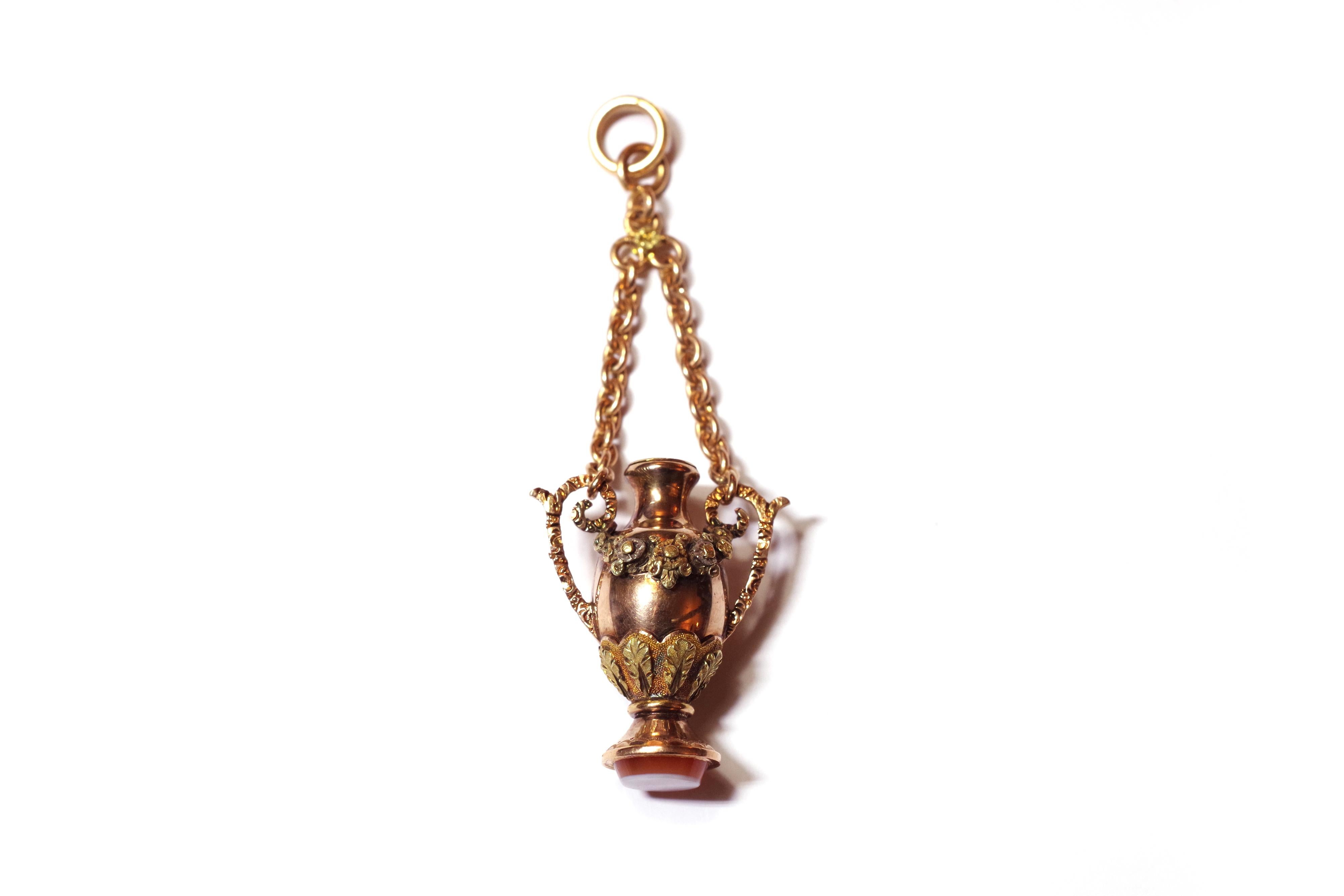 Victorian amphora bottle pendant in yellow, pink and green gold 18 karats. This antique pendant is in the form of an amphora with an opening lid. The amphora is delicately decorated with a garland of flowers and leaf in yellow and green gold. The