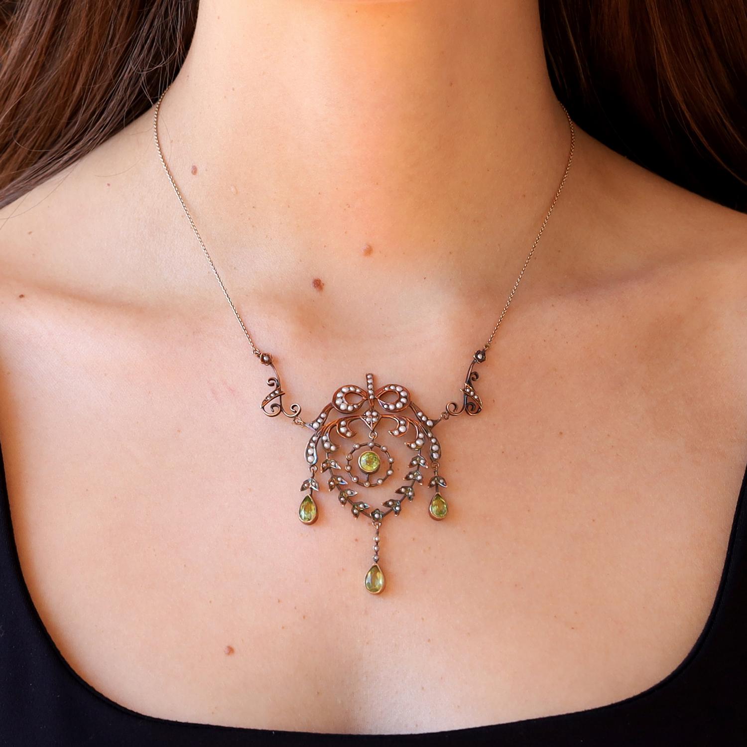 De la época victoriana, más concretamente del Romanticismo, este exquisito collar en guirnalda está adornado con vibrantes peridotos verdes y lustrosas y cremosas perlas de siembra. Rematada con un precioso lazo, un colgante central rodeado de