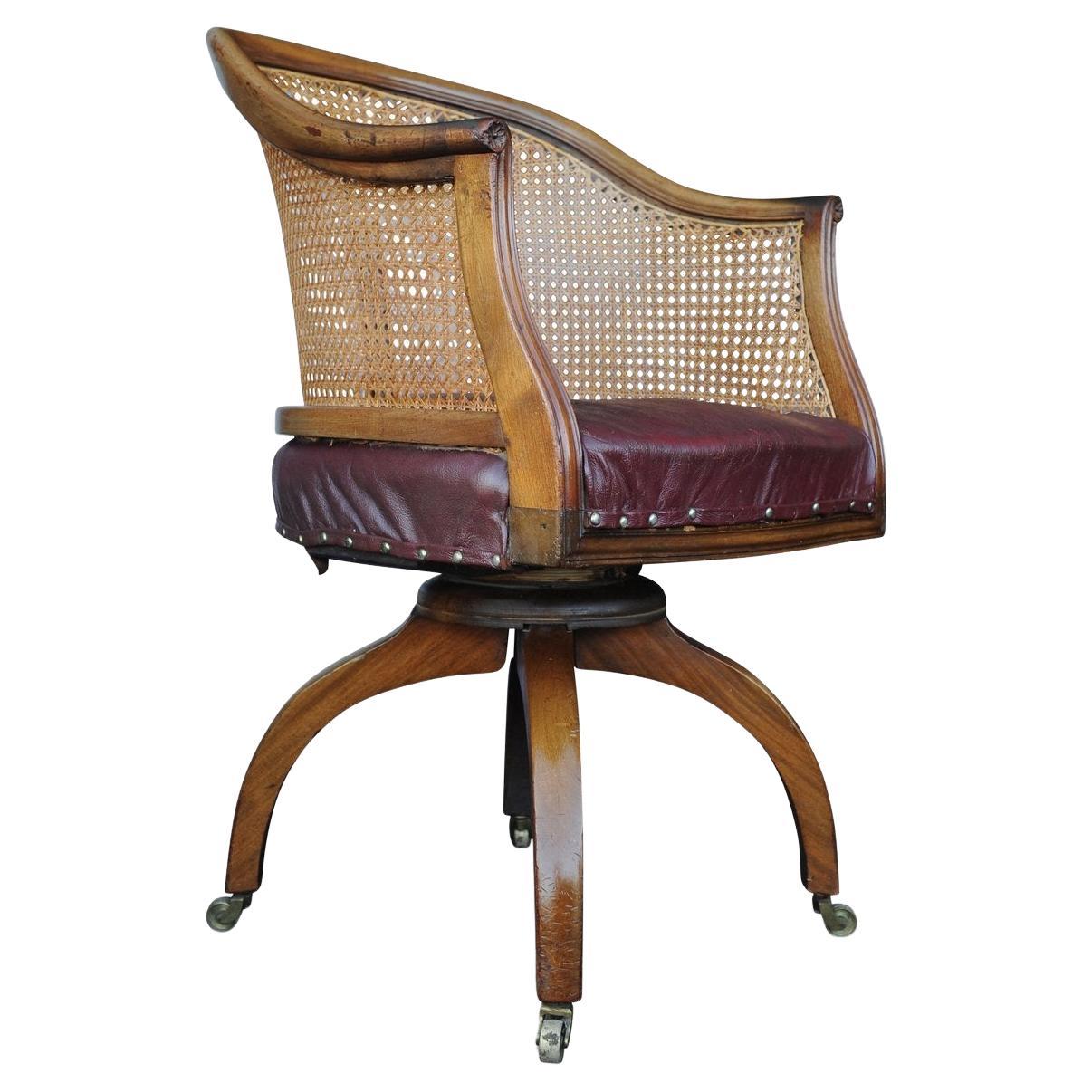 An elegant and rare, Early Victorian antique Bergere library, office, desk, swivel armchair with original maroon leather seat & stud details, on a claw base with
Castors.

The chair has a feel of the elegant Regency period for the seat and cane