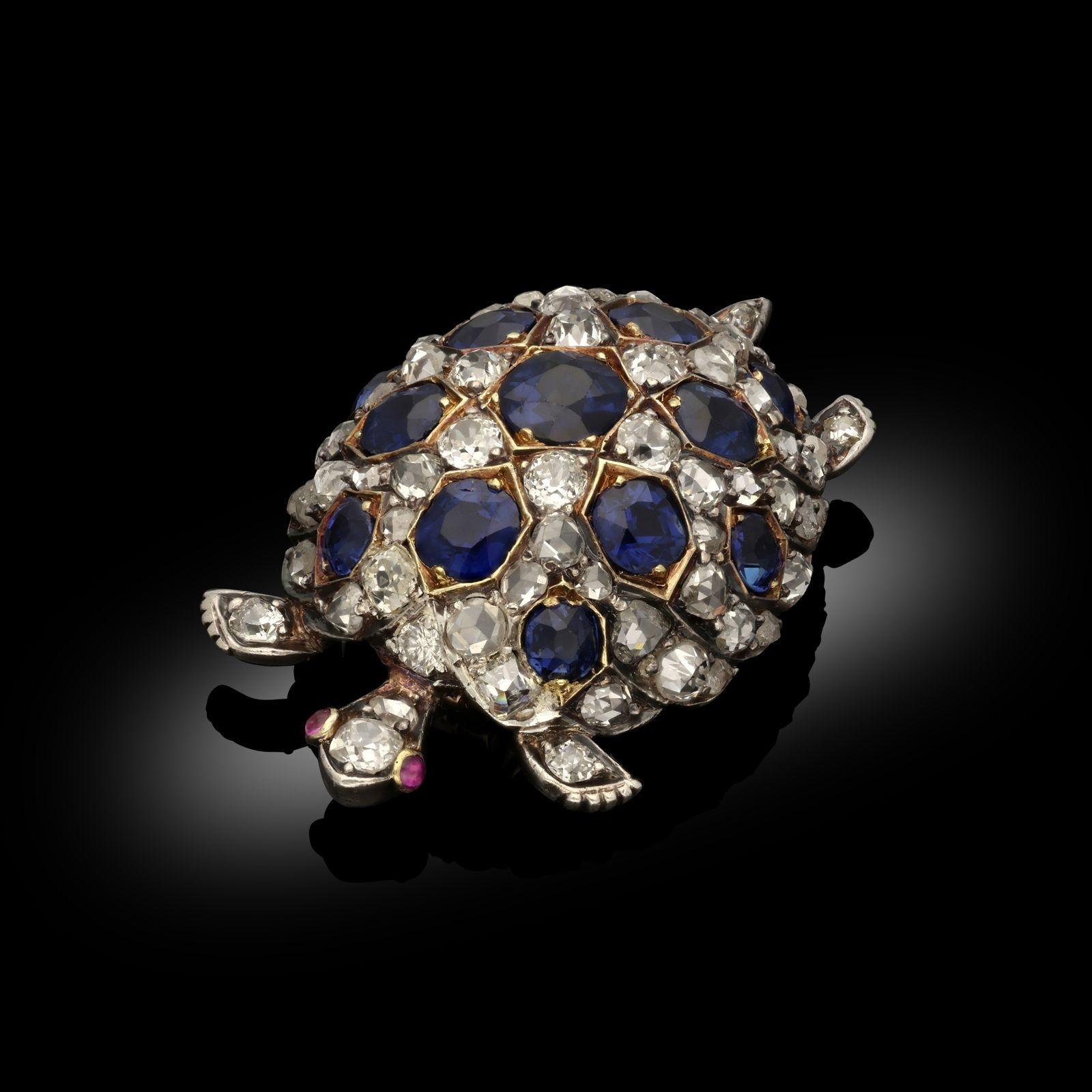 An antique tortoise brooch, circa 1870. The tortoise is of a realistic design with a high domed shell, set with old cut diamonds and cushion cut sapphires. The sapphires are set in yellow gold depicting a characteristic tortoise shell pattern. The