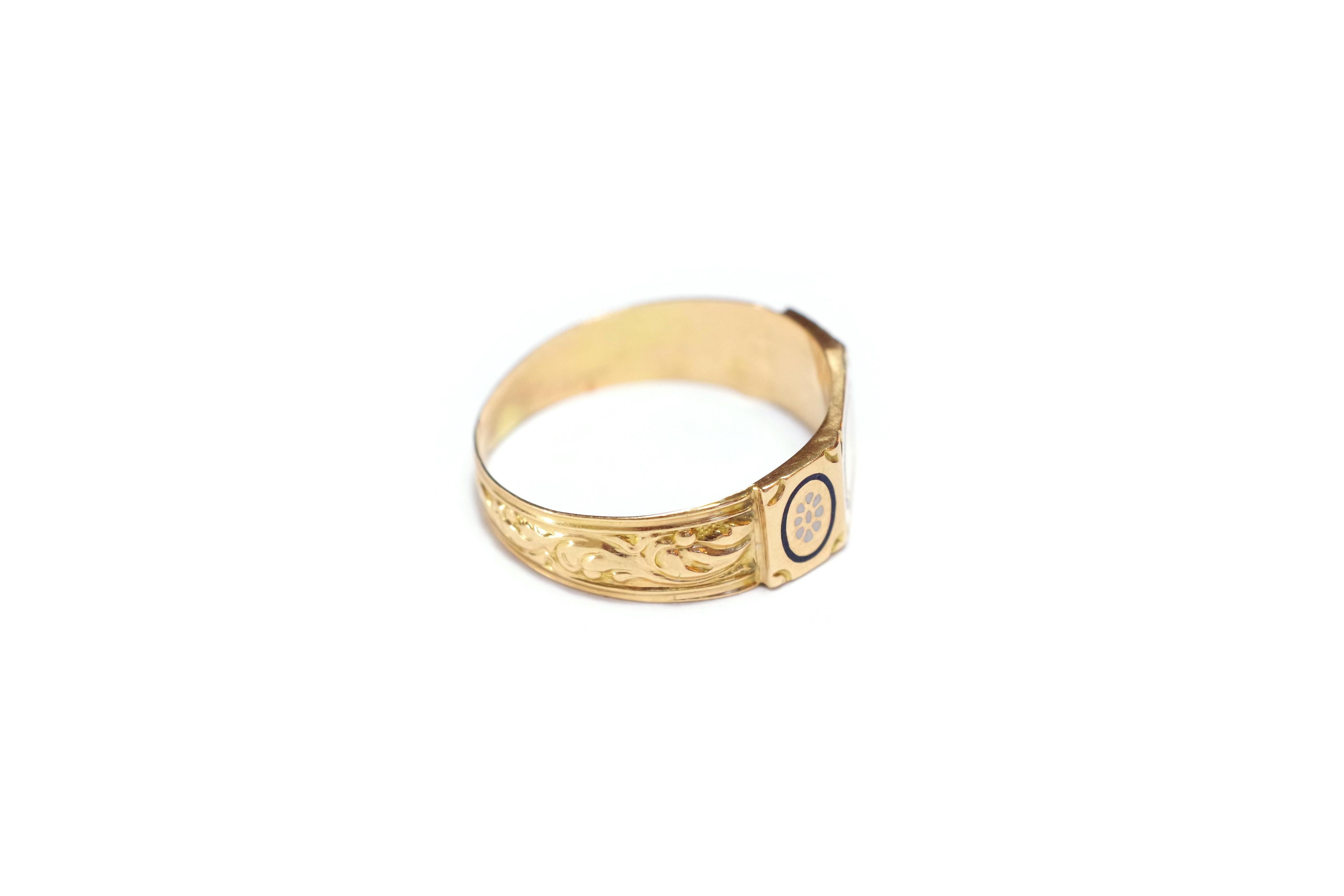 Victorian antique French wedding ring in 18 karat yellow and rose gold. The ring has three facets: the sides are decorated with cartouches with white enamelled flowers surrounded by a blue border on a golden background. In the centre, a blank