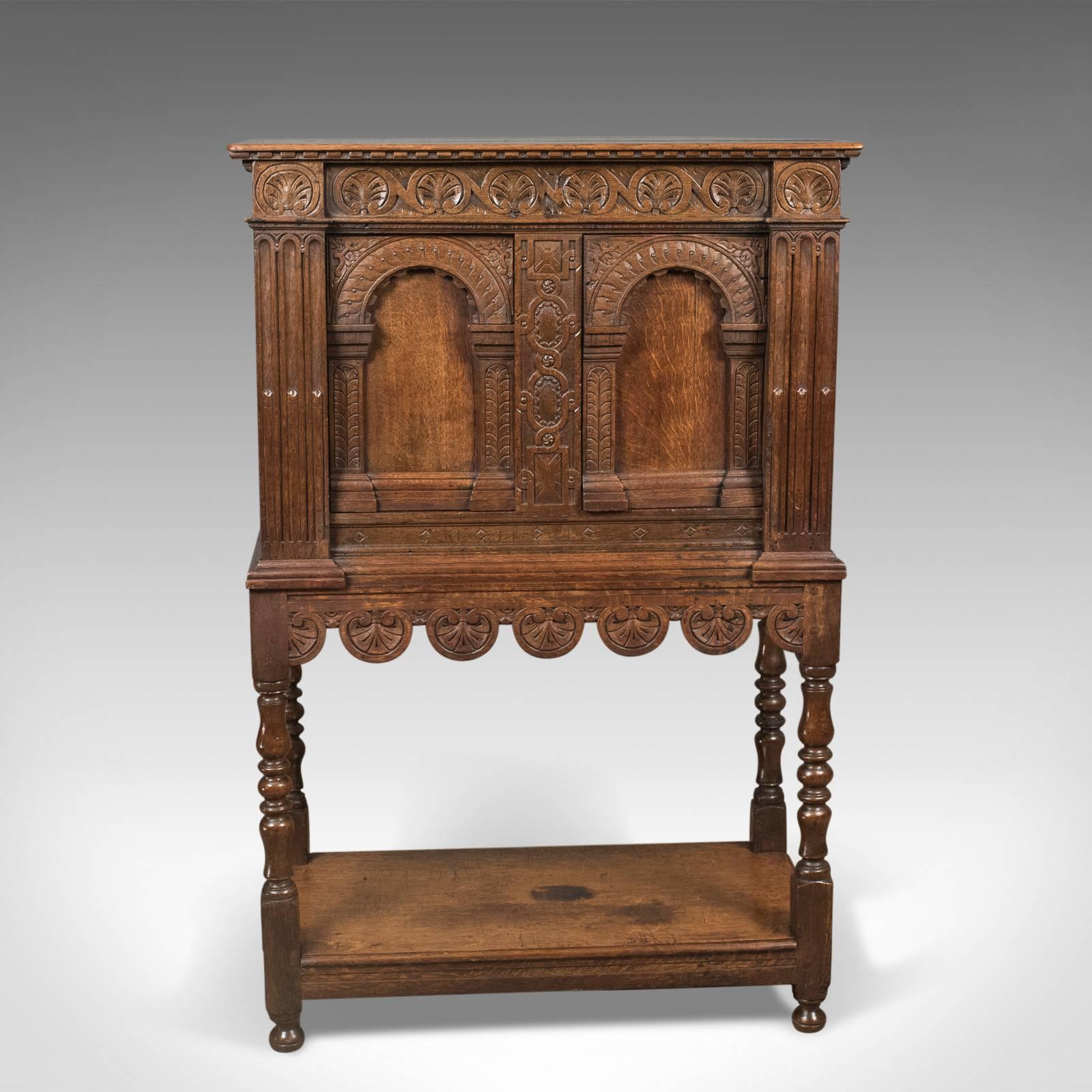 This is a Victorian antique livery cupboard in the 17th century taste, English oak, circa 1880.

Warm hues and grain interest in the English oak
Richly decorated with carved detail
Raised on turned legs united by lower display tier

Planked