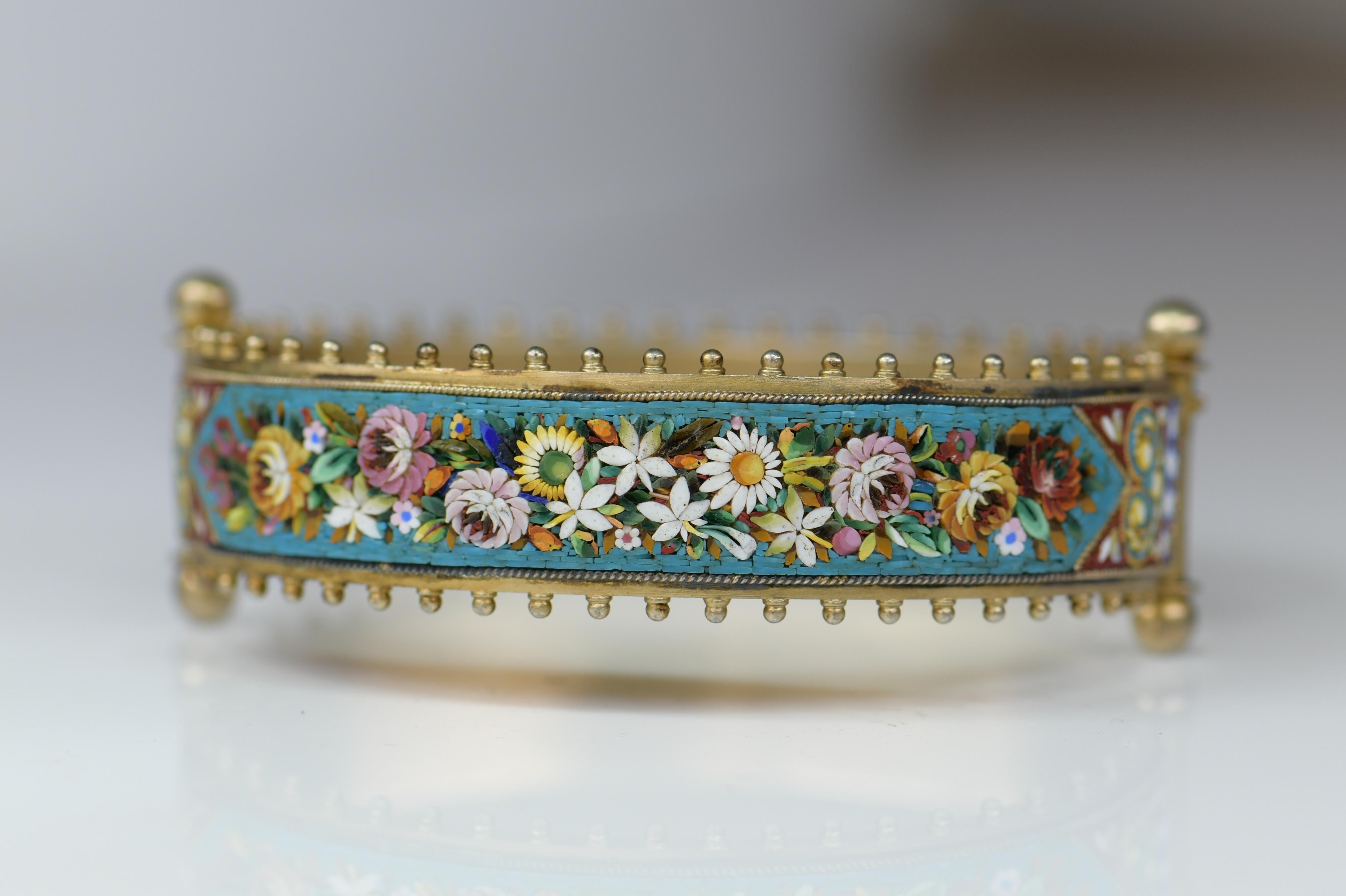 A fantastic micro mosaic bracelet from the Victorian (ca1880) era. Made of gilded silver, the bangle style bracelet has a fairly wide surface with a marvelous micro-mosaic design on both front and back. 

Tiny tiles with vivid colors of glass have