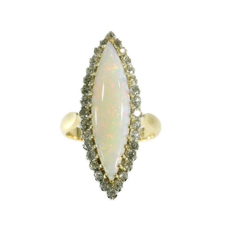 This 18K yellow gold Victorian ring from 1880 has a grand navette shaped cabochon cut opal as your personal wishing well full of red and green shimmers surrounded with 32 old brilliant cut diamonds set in platinum. This ravishing navette with a