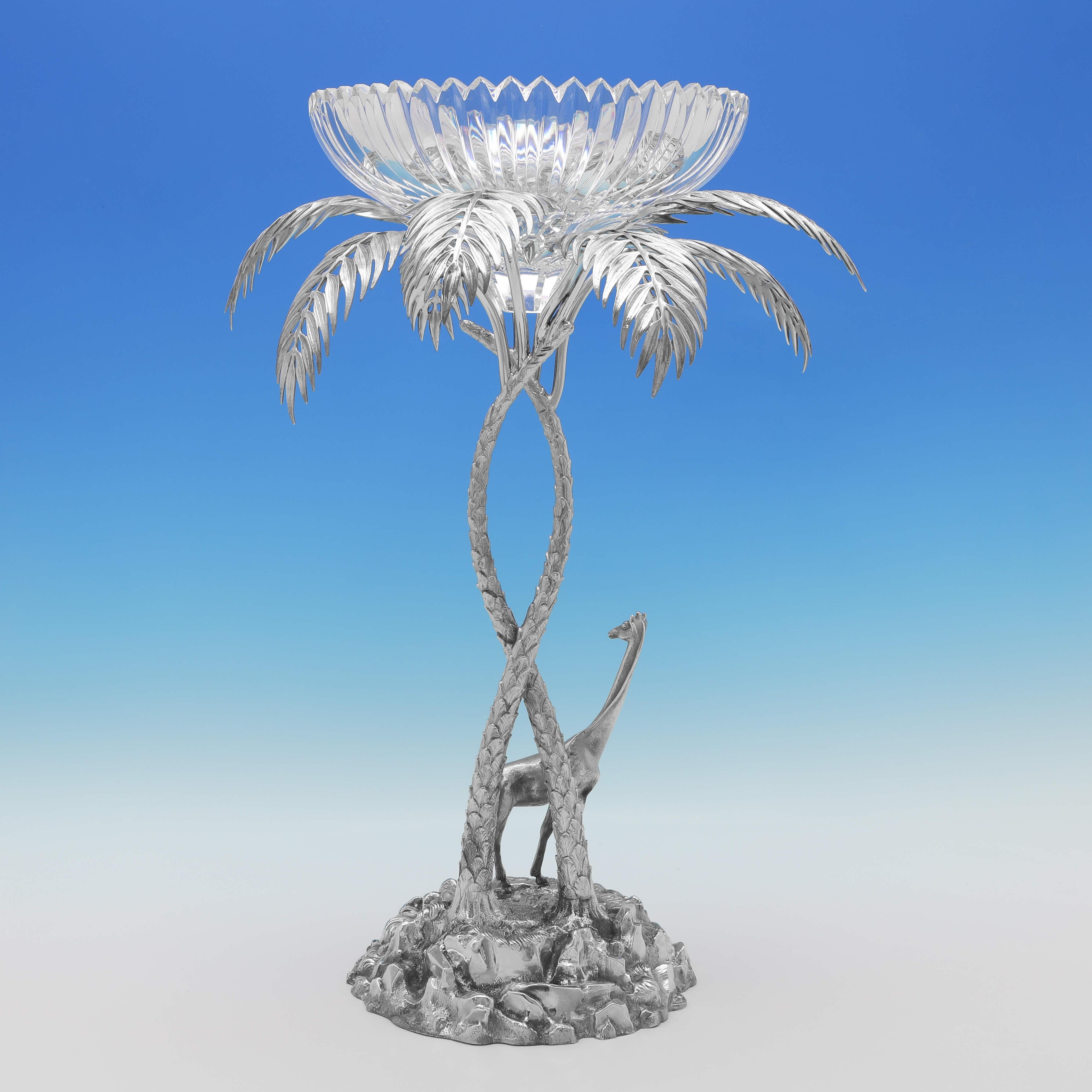 Made circa 1890, this charming, Antique Silver plate centrepiece, is of naturalistic form, modelled to look like a palm tree with a giraffe under the fronds, and supporting a glass bowl for fruit or flowers. 

The centrepiece measures 22