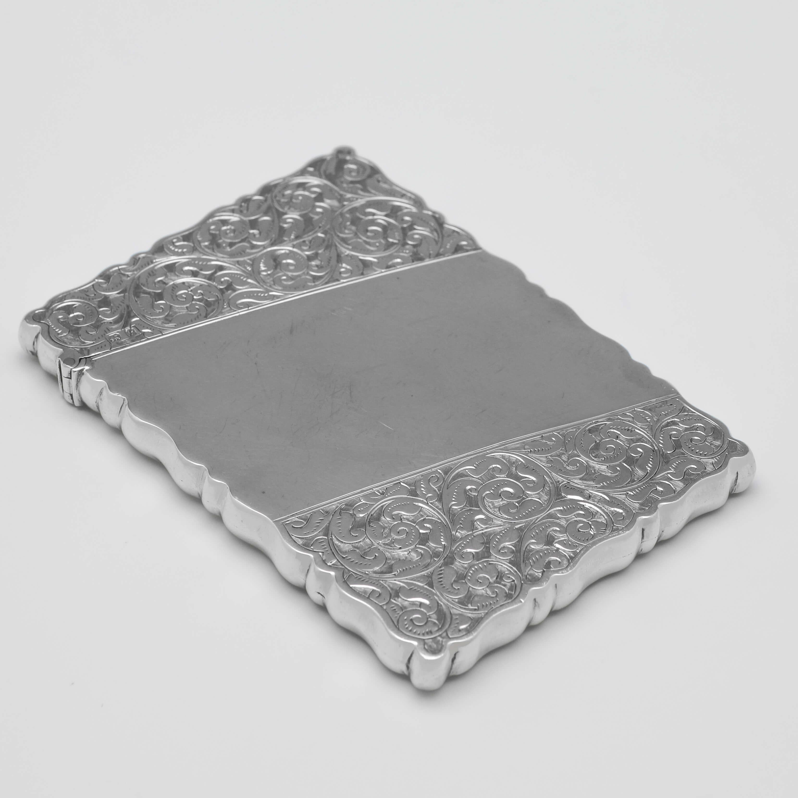Hallmarked in Chester in 1898 by John Millward Banks, this attractive, Victorian, Antique Sterling Silver Card Case, features shaped sides, and floral scroll engraving. 

The card case measures 3.75