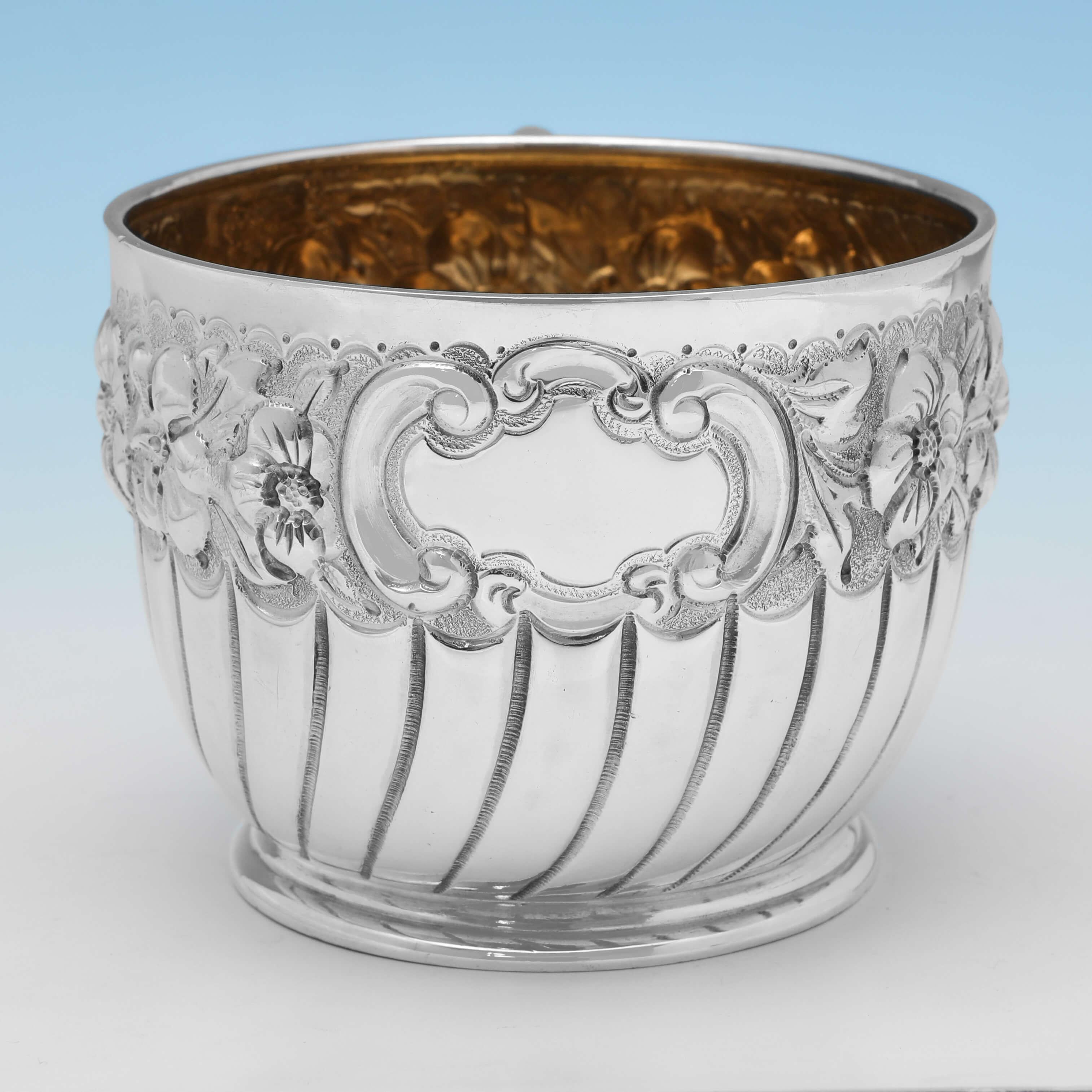 Hallmarked in London in 1896 by Charles Edwards, this attractive, Antique Sterling Silver Christening Mug, features swirled half fluting, a chased floral border and a gilt interior. 

The christening mug measures 2.5