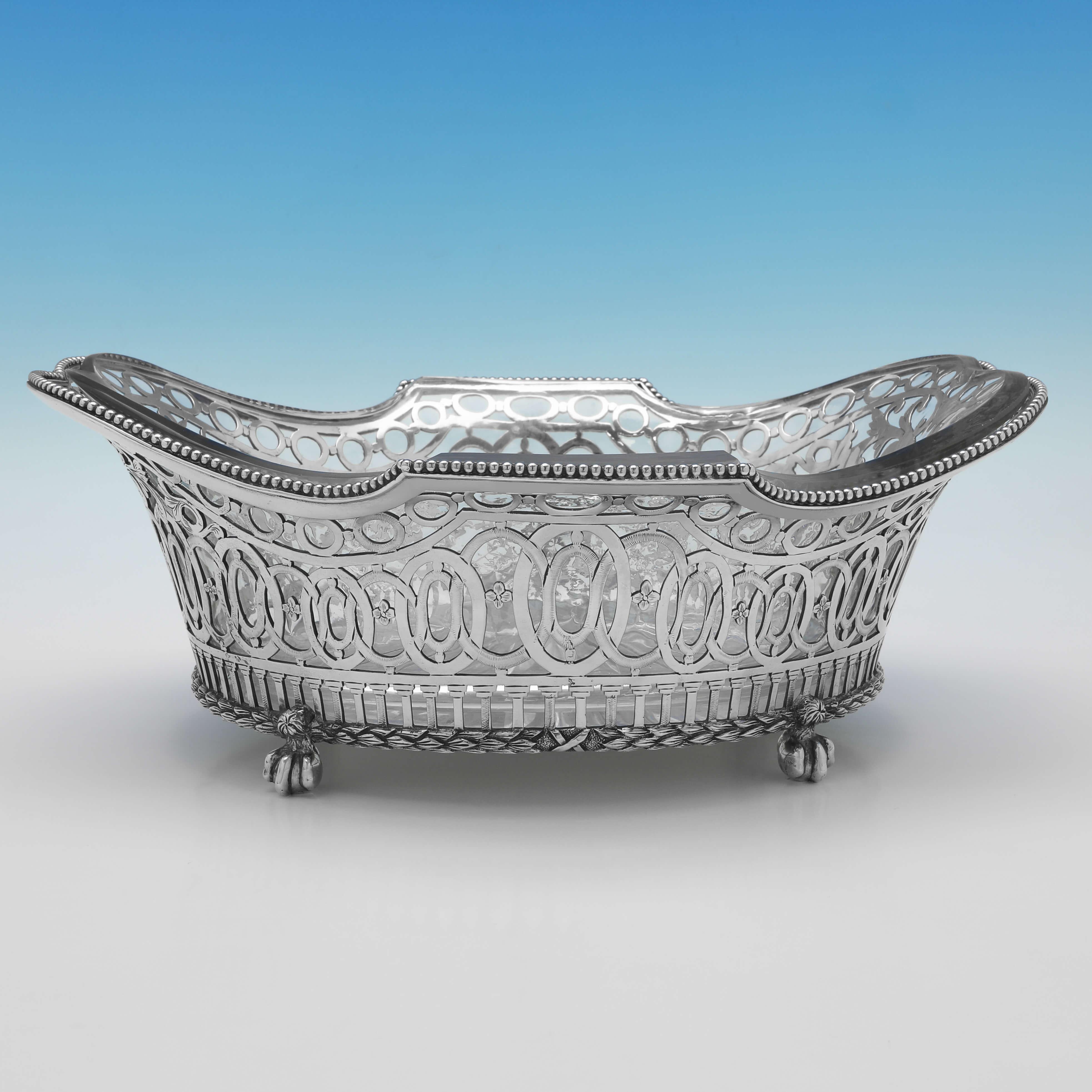 Hallmarked in London in 1890 by Dobson & Sons, this attractive, Victorian, antique sterling silver dish, stands on 4 ball and claw feet, and features bead detailing, pierced and engraved decoration and a glass liner. 

The dish measures 4.5