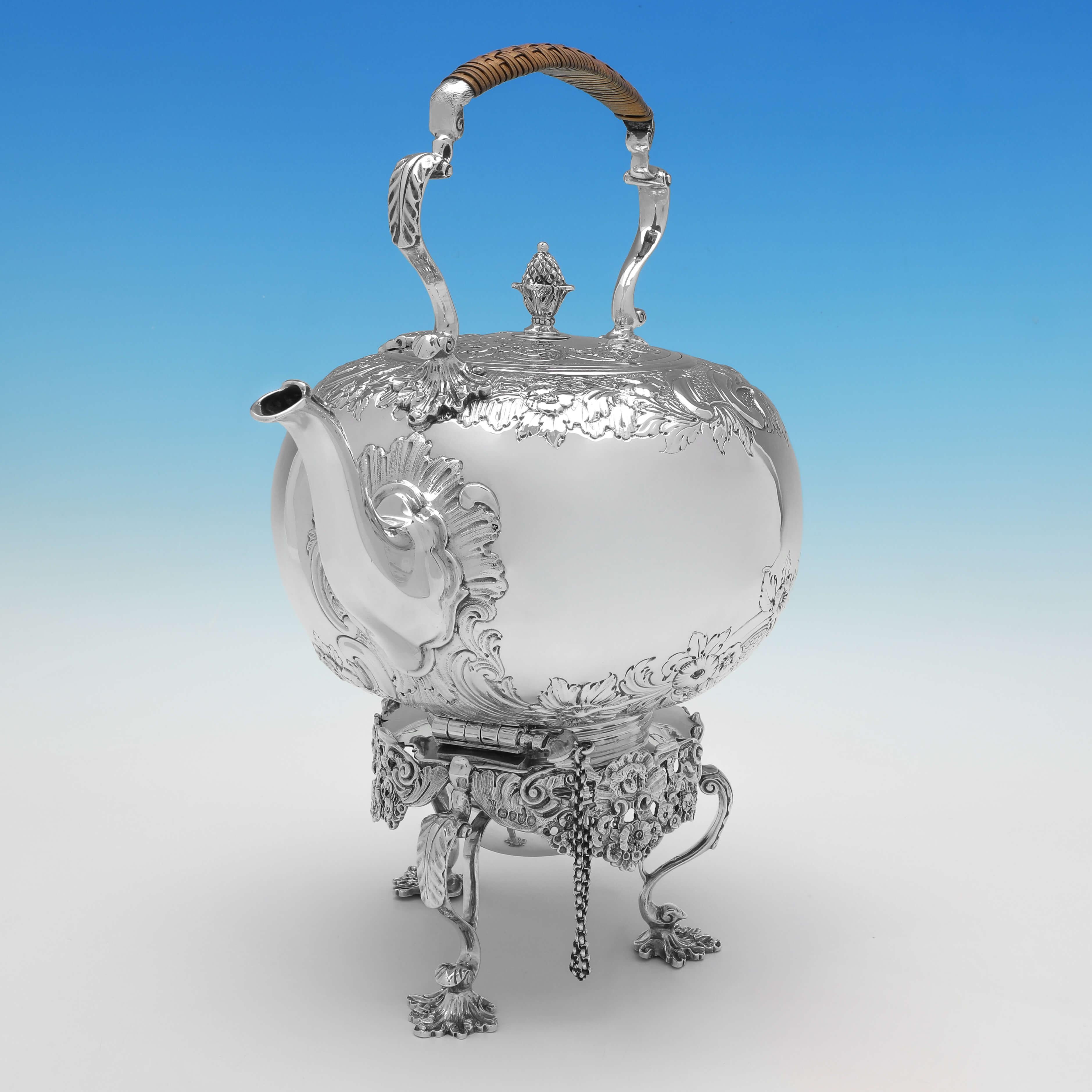 Hallmarked in London in 1882 by Daniel & Charles Houle, this attractive, Victorian, Antique Sterling Silver Kettle, features a cast stand which holds a spirit burner, flat chased decoration to the body and lid, and a wicker handle. 

The kettle