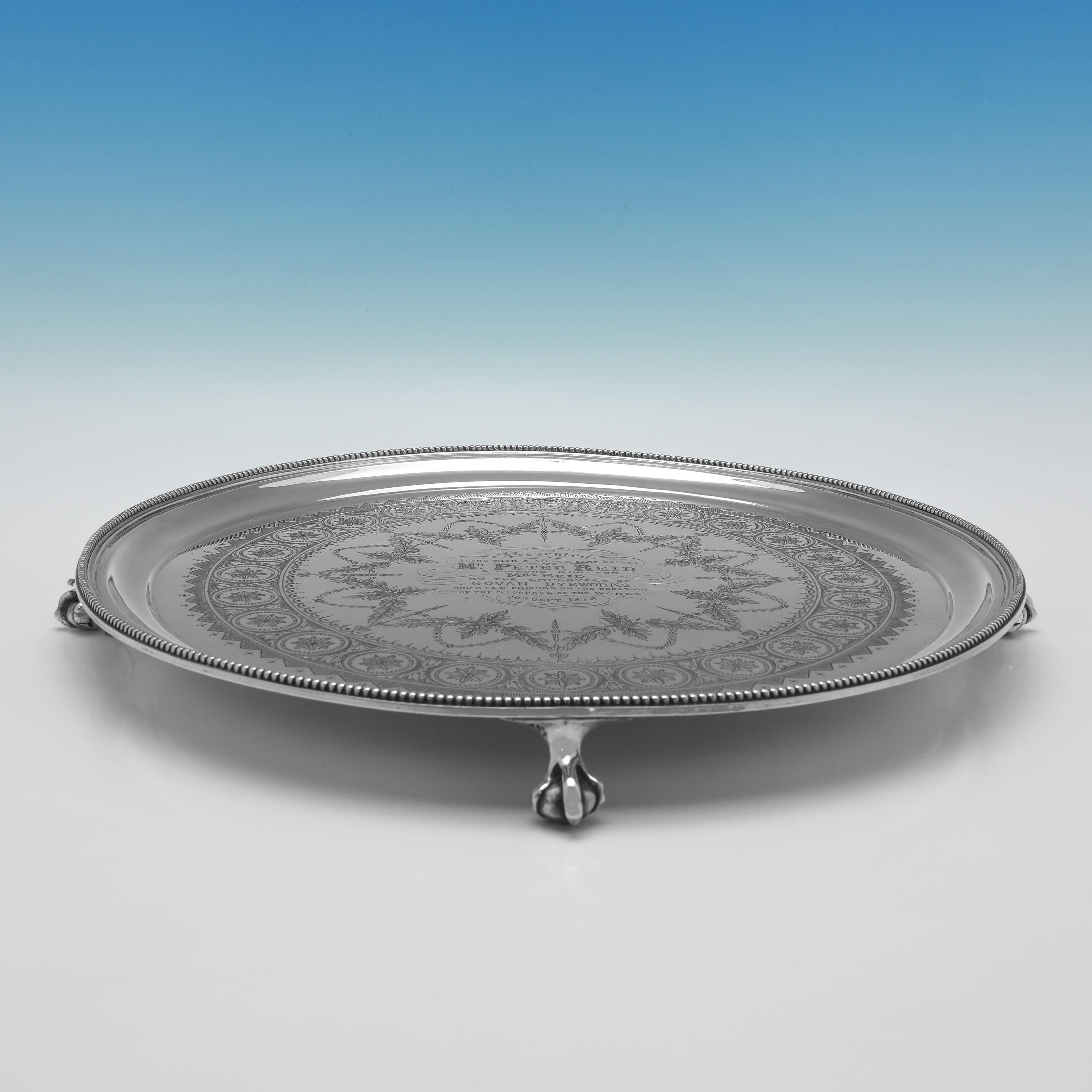 Hallmarked in London in 1875 by Henry Wilkinson & Co., this attractive, Antique Sterling Silver Salver, stands on ball and claw feet, and features a bead border, engraved decoration, and an engraved presentation inscription to the centre. 

The