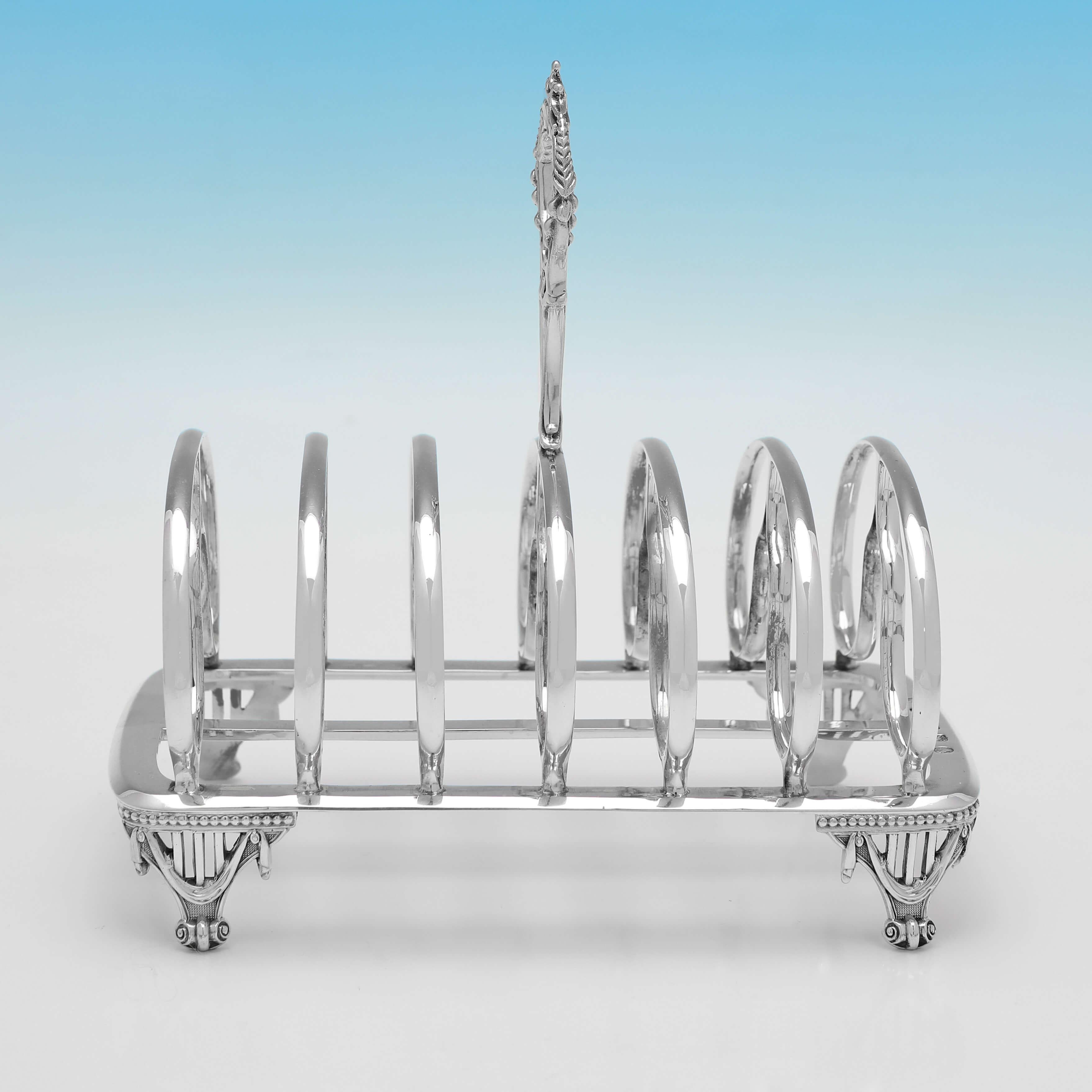 Hallmarked in Birmingham in 1862 by Elkington & Co., this attractive, Victorian, Antique Sterling Silver Toast Rack, is ornate in design, with a cast neoclassical handle and 4 feet, and will hold 6 pieces of toast. 

The toast rack measures