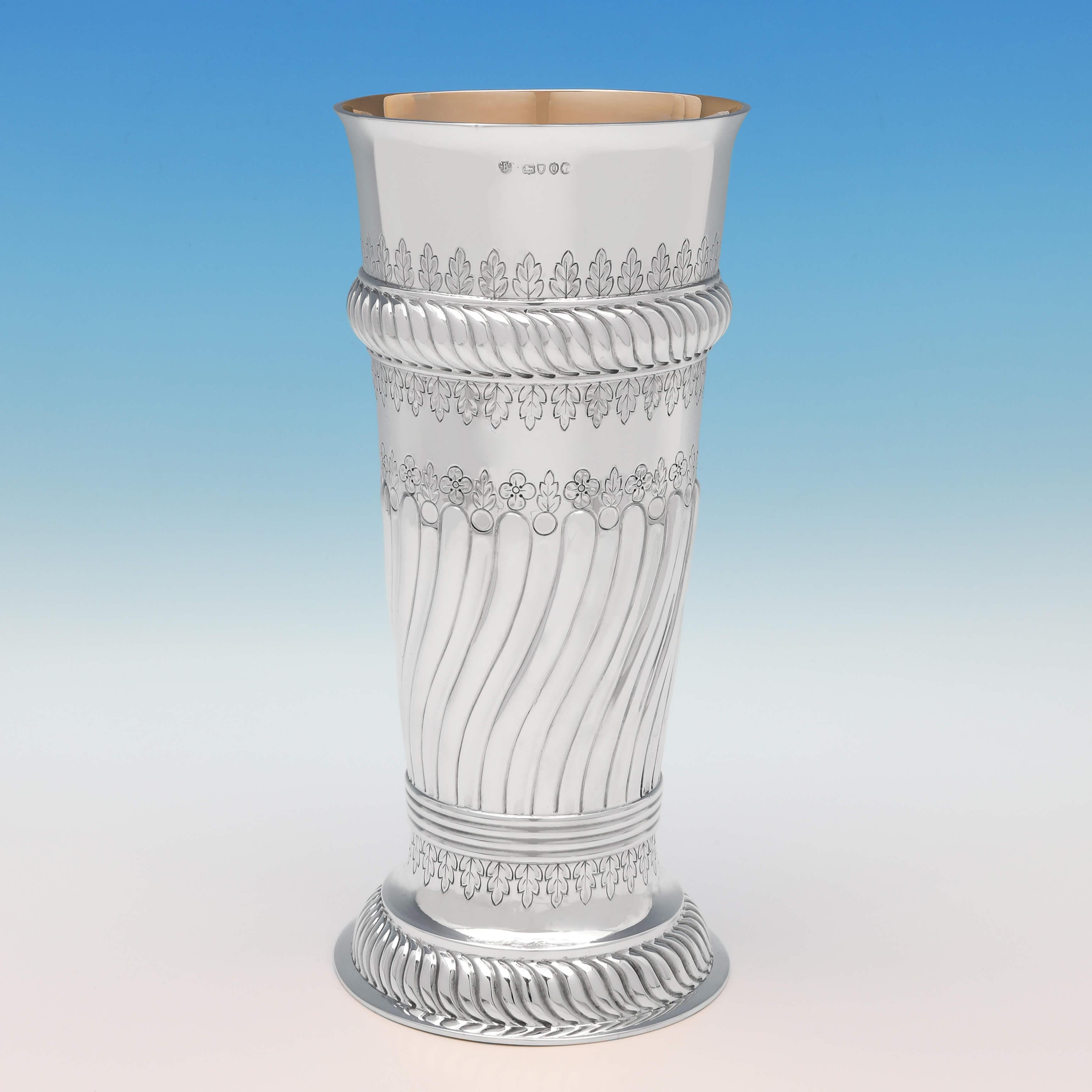 Hallmarked in London in 1889 by Barnards, this attractive, Victorian, antique sterling silver vase, features swirled fluting, chased decoration throughout, and a gilt interior. The vase measures: 10.5